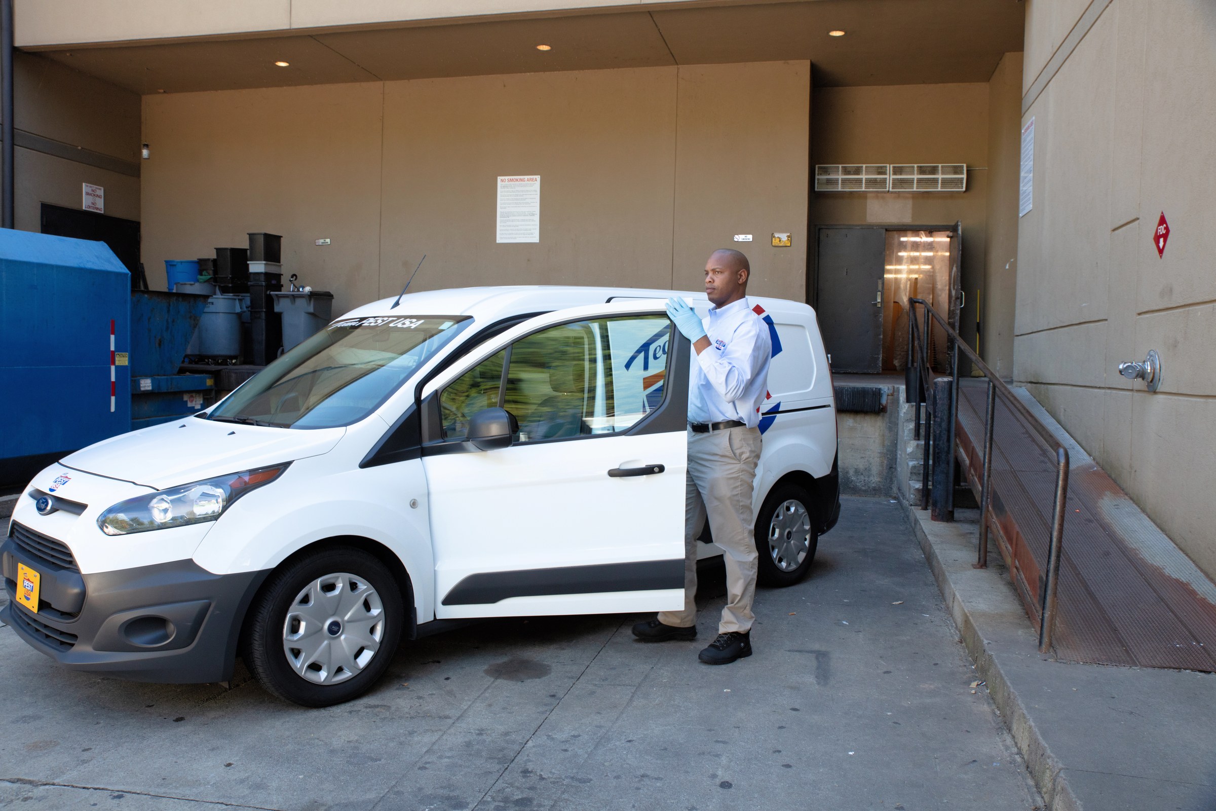 Team Pest USA technician beside a branded service van at a commercial property.