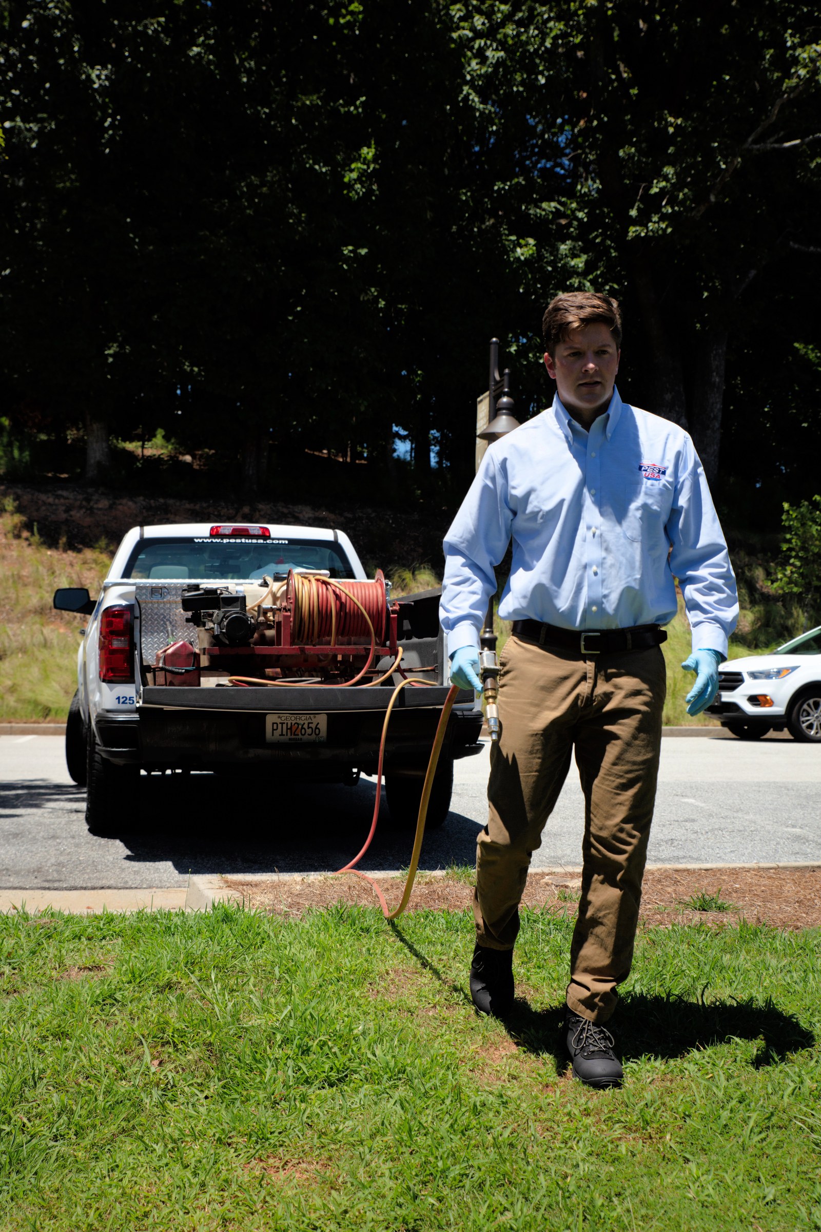 Team Pest USA technician carrying a treatment hose from a service truck.