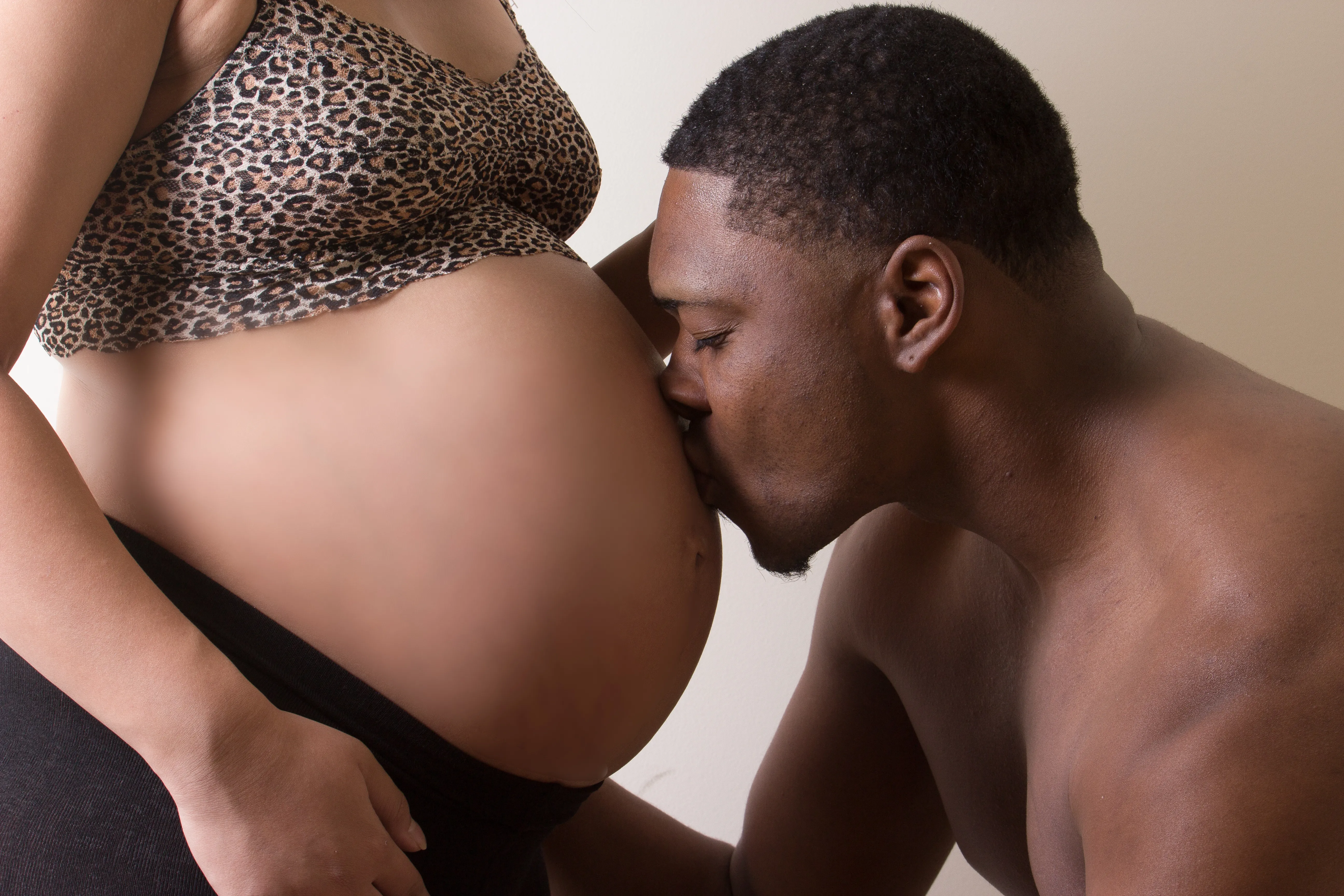 Kristen's partner kissing her belly during an at-home maternity session