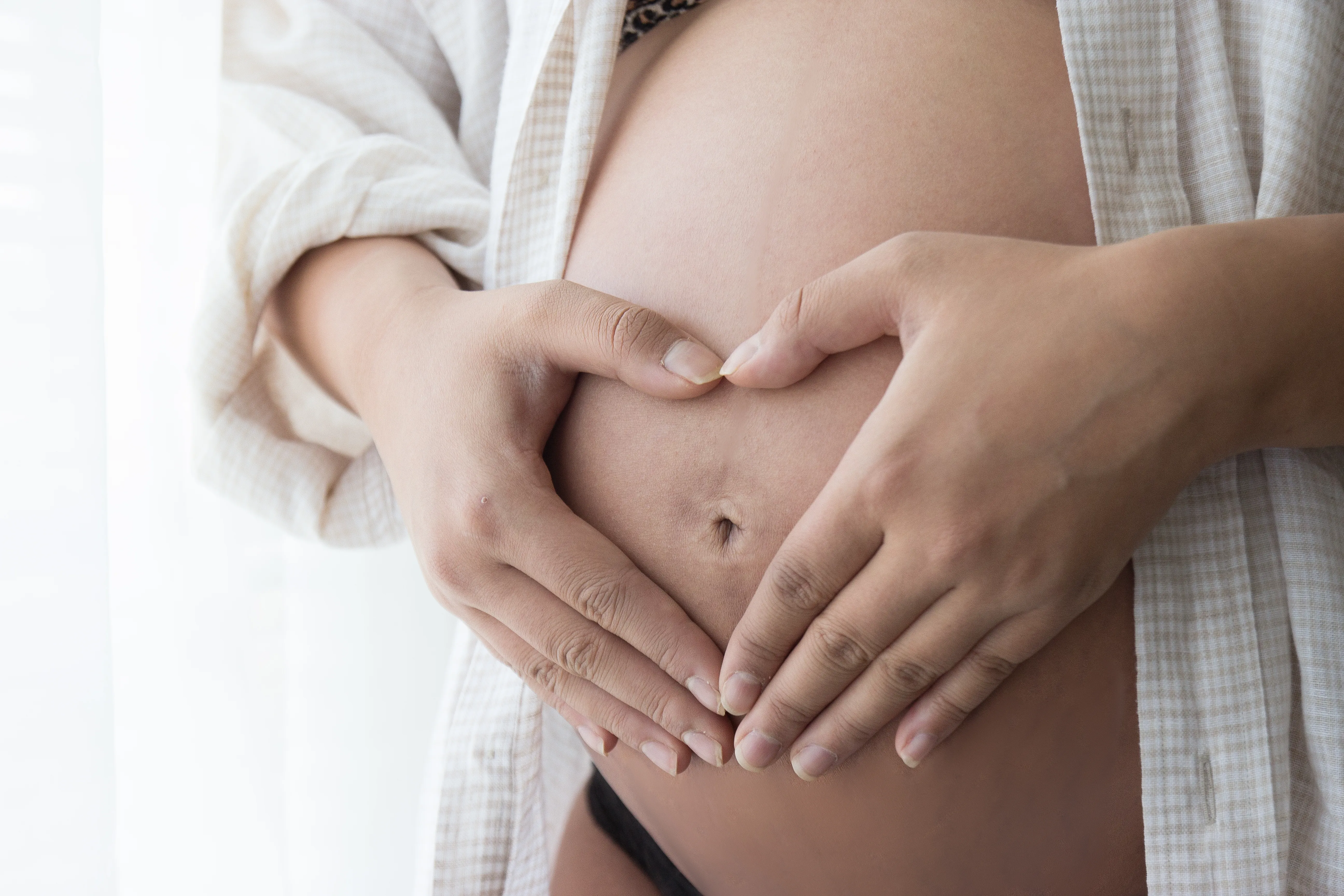 Kristen with her hands resting on her belly during an at-home maternity session