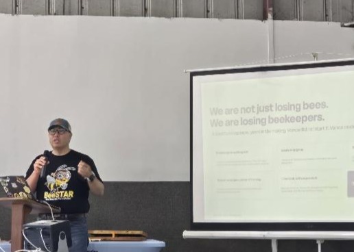 The image depicts a presentation slide with text emphasizing the decline in beekeepers, attributing it to factors like Varroa, and promoting a program called Bee Smarter, Farm Better.AI-generated content may be incorrect.