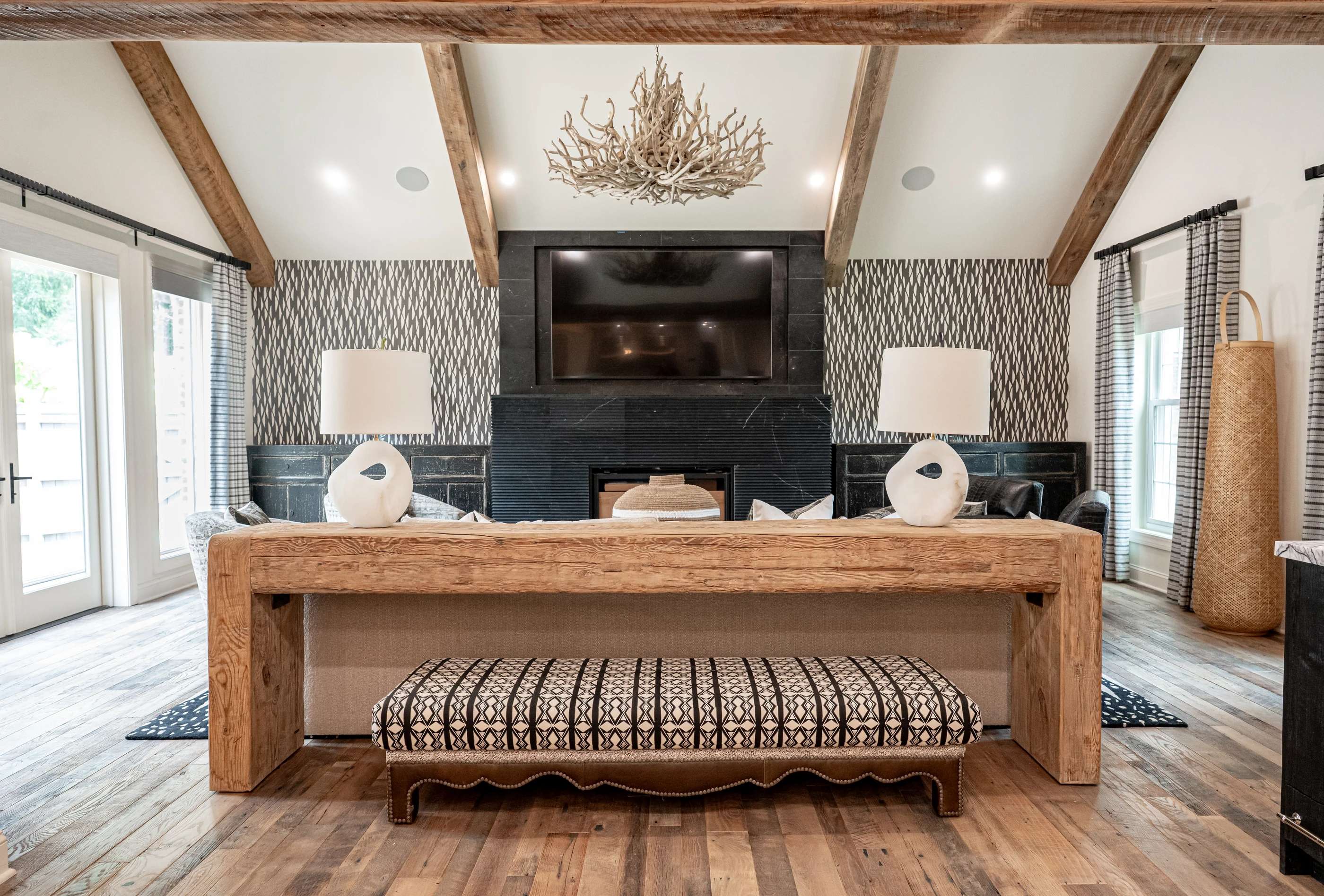 Hart living room with timber beams, sculptural lighting, patterned seating and a graphic rug.