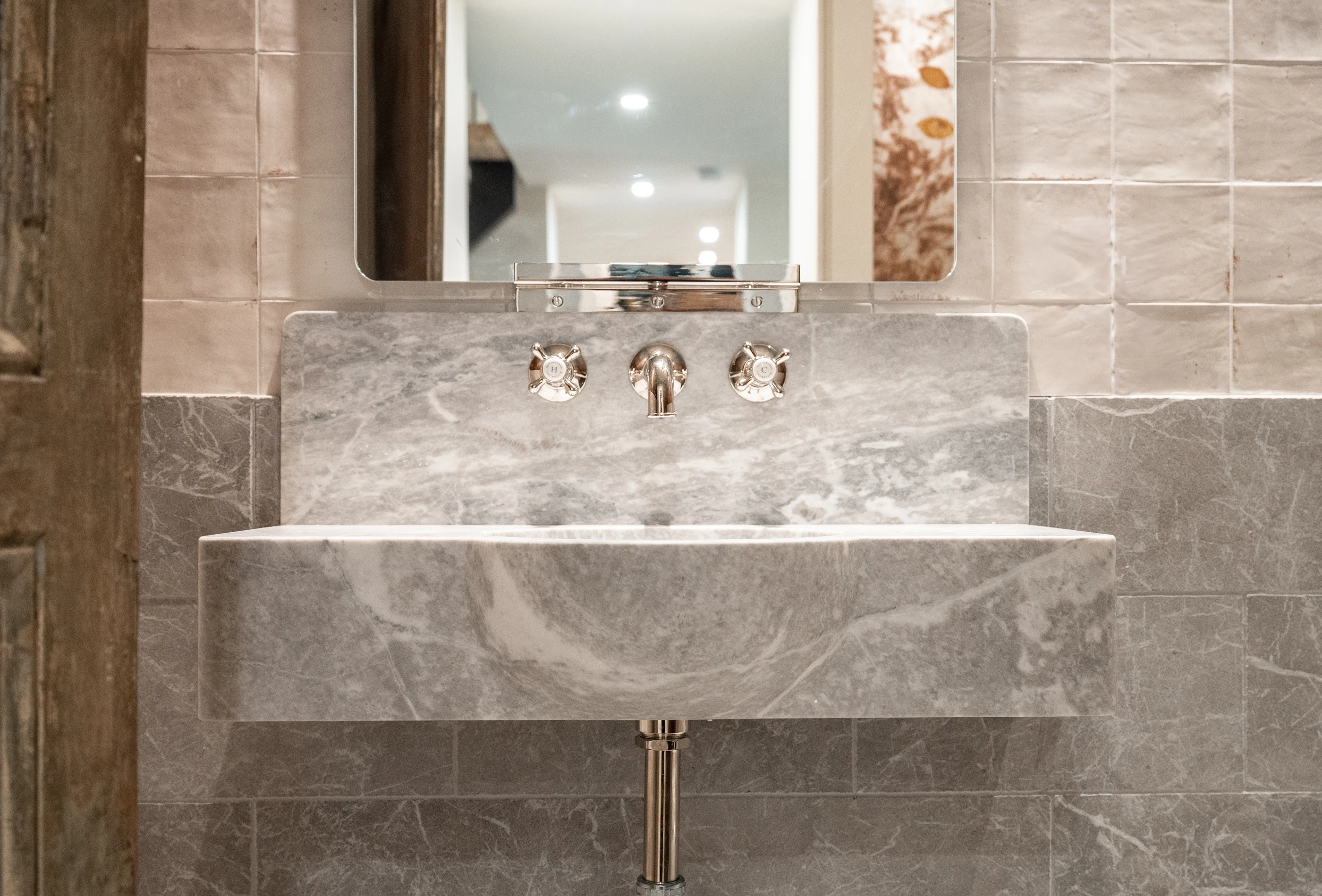 Hart bathroom with a sculptural veined stone vanity and polished fixtures.