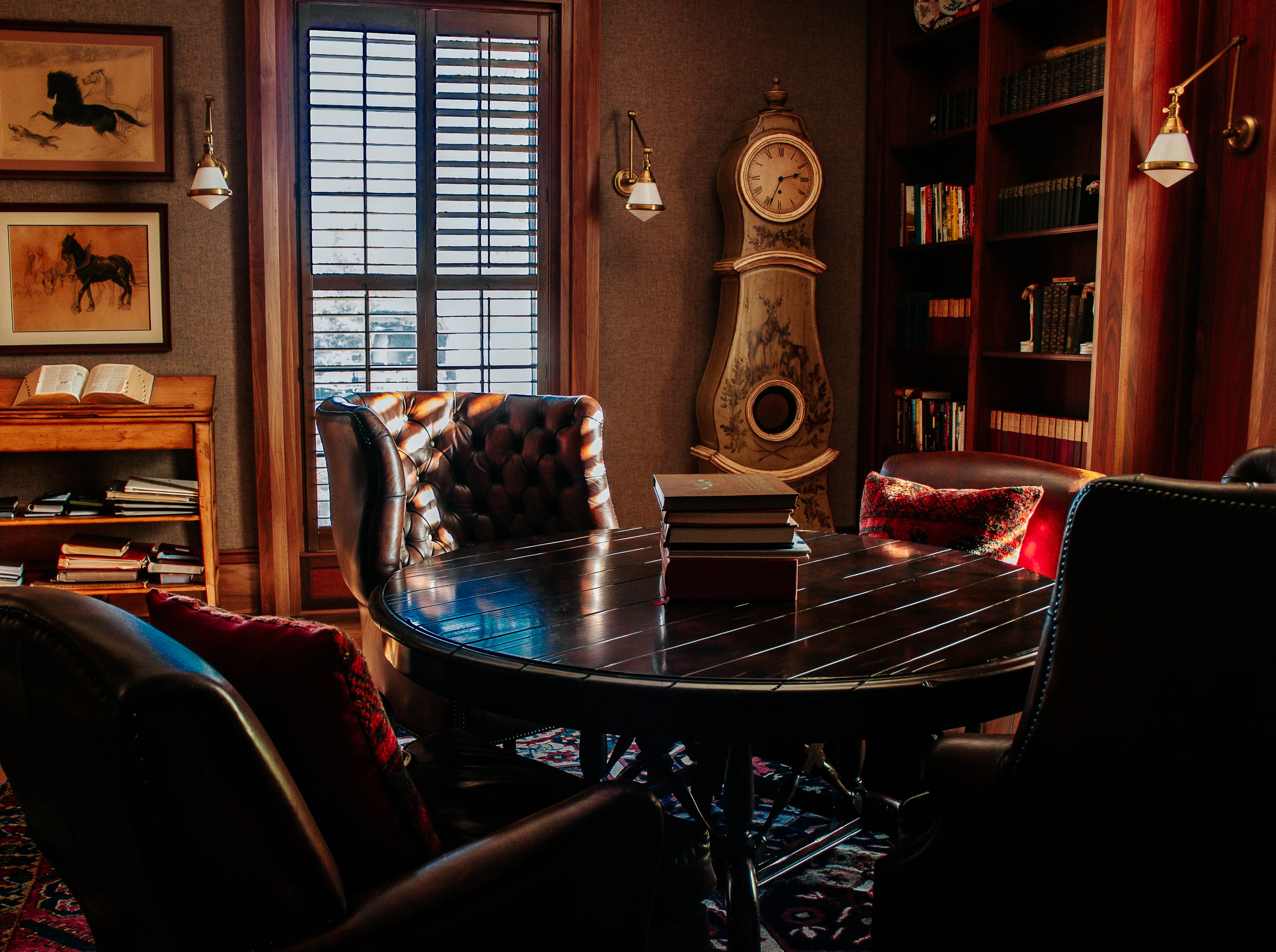 Reed Farm library with leather seating, timber bookshelves, an antique clock and equestrian artwork.