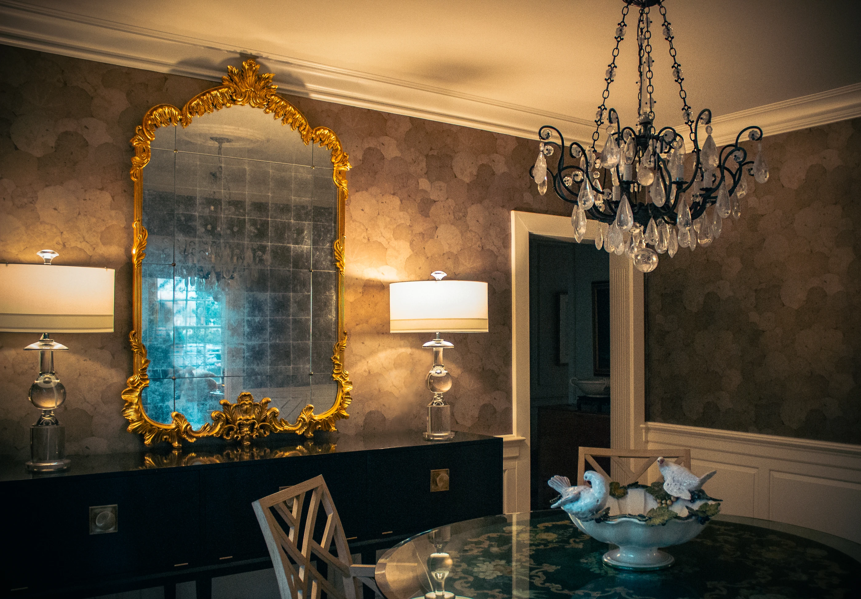 Ashland Park dining room with a gilt mirror, chandelier and patterned wallcovering.