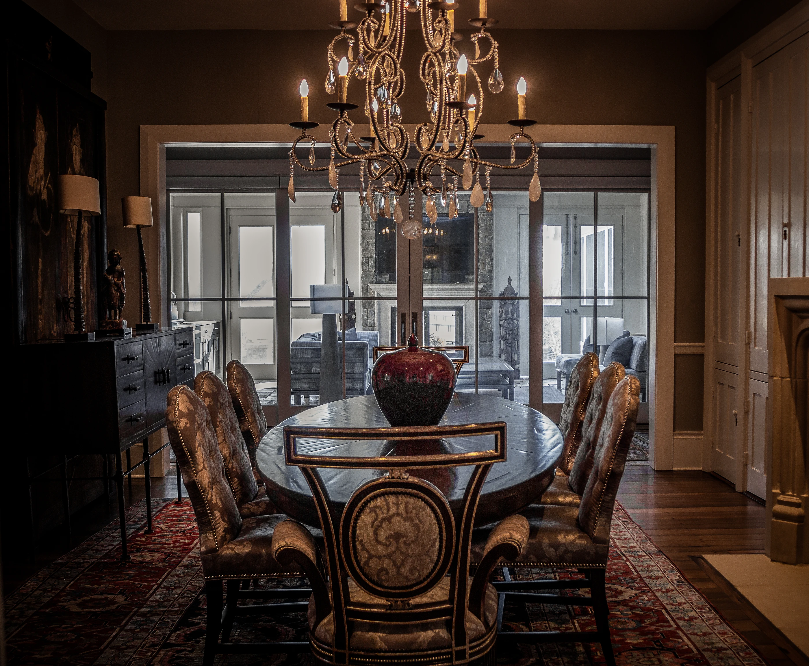 Jessamine County Farm dining room with antique seating, a crystal chandelier and a patterned red rug.