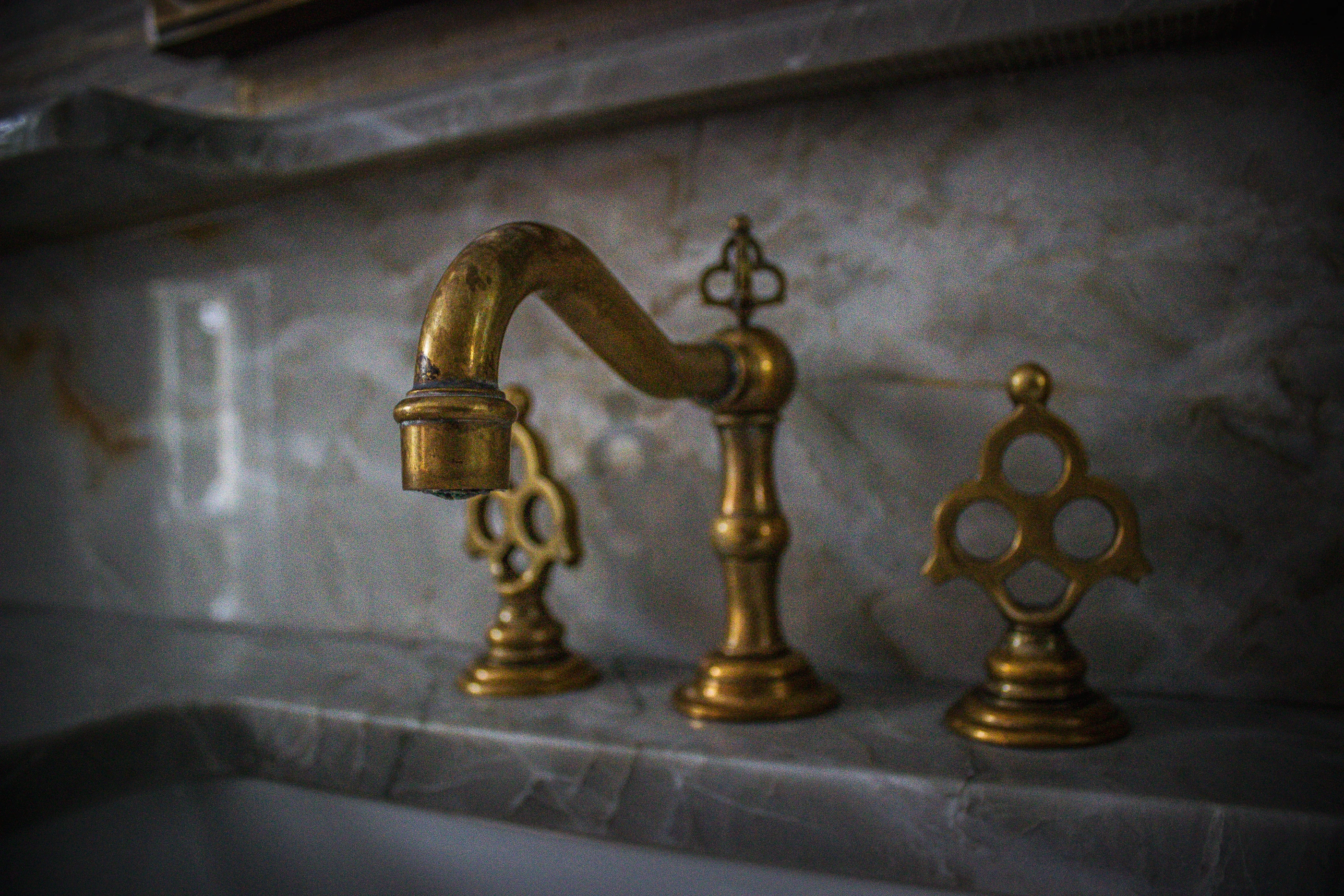 Ashland Park aged brass fixtures against richly veined stone.