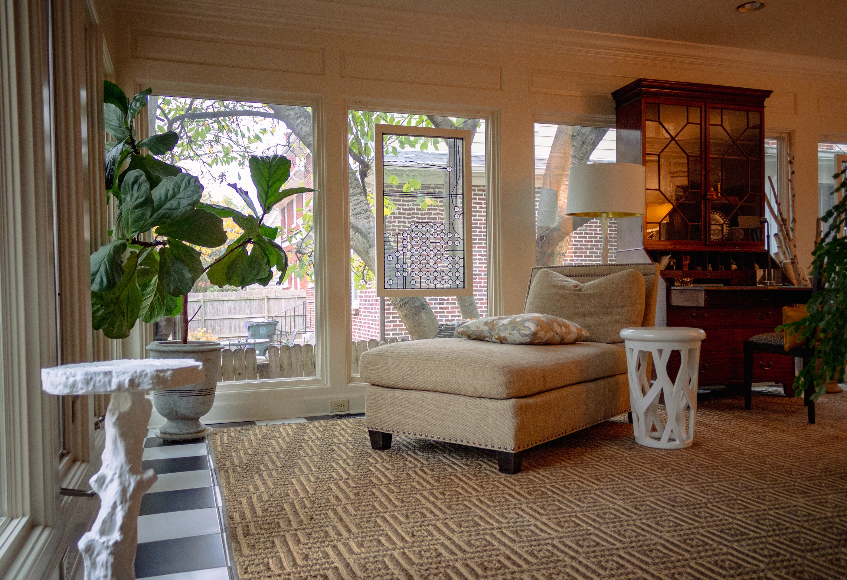 Ashland Park sunroom with a chaise, glazed doors, a woven rug and a display cabinet.