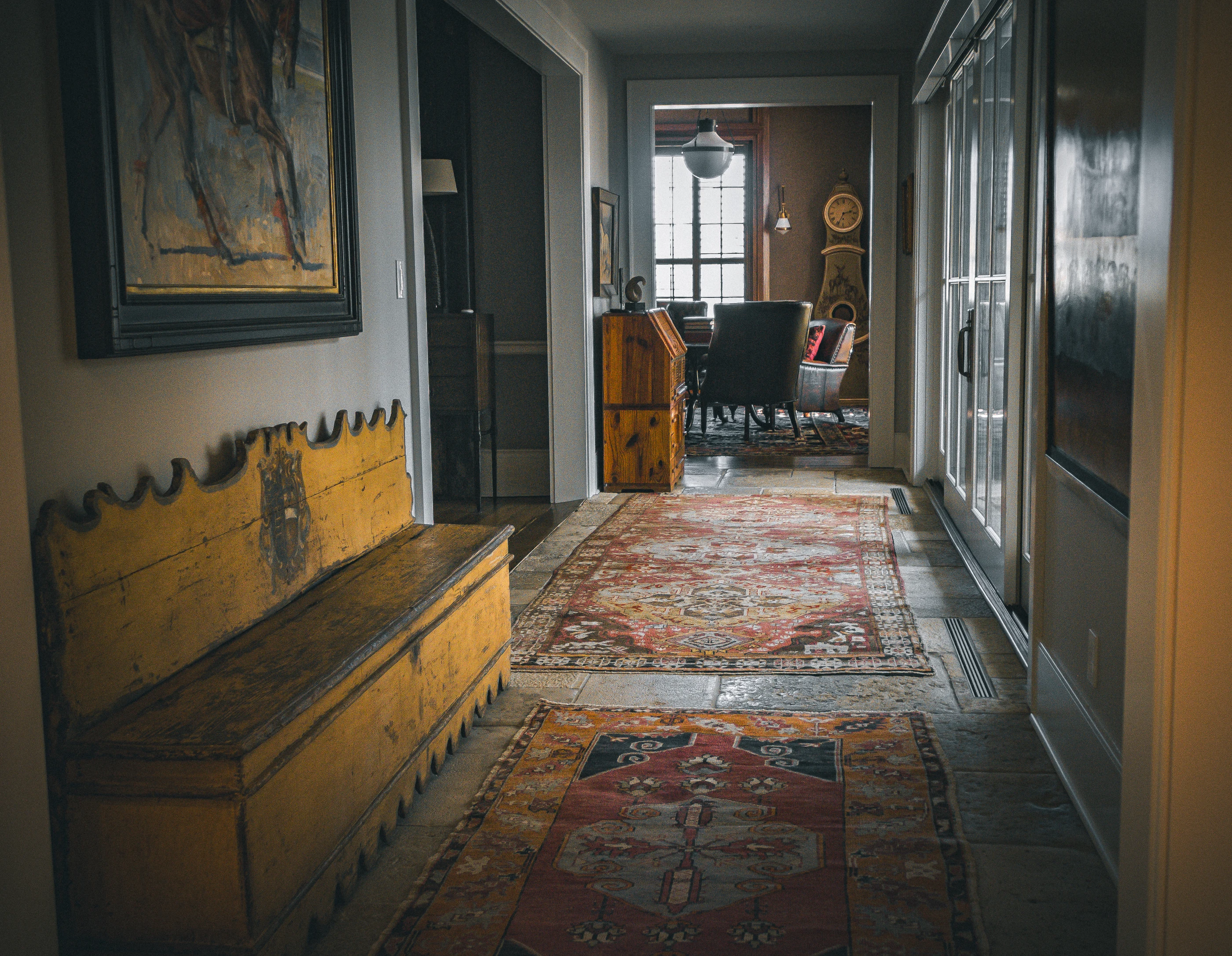 Jessamine County Farm gallery hall with antique seating, patterned rugs and a view into the library.