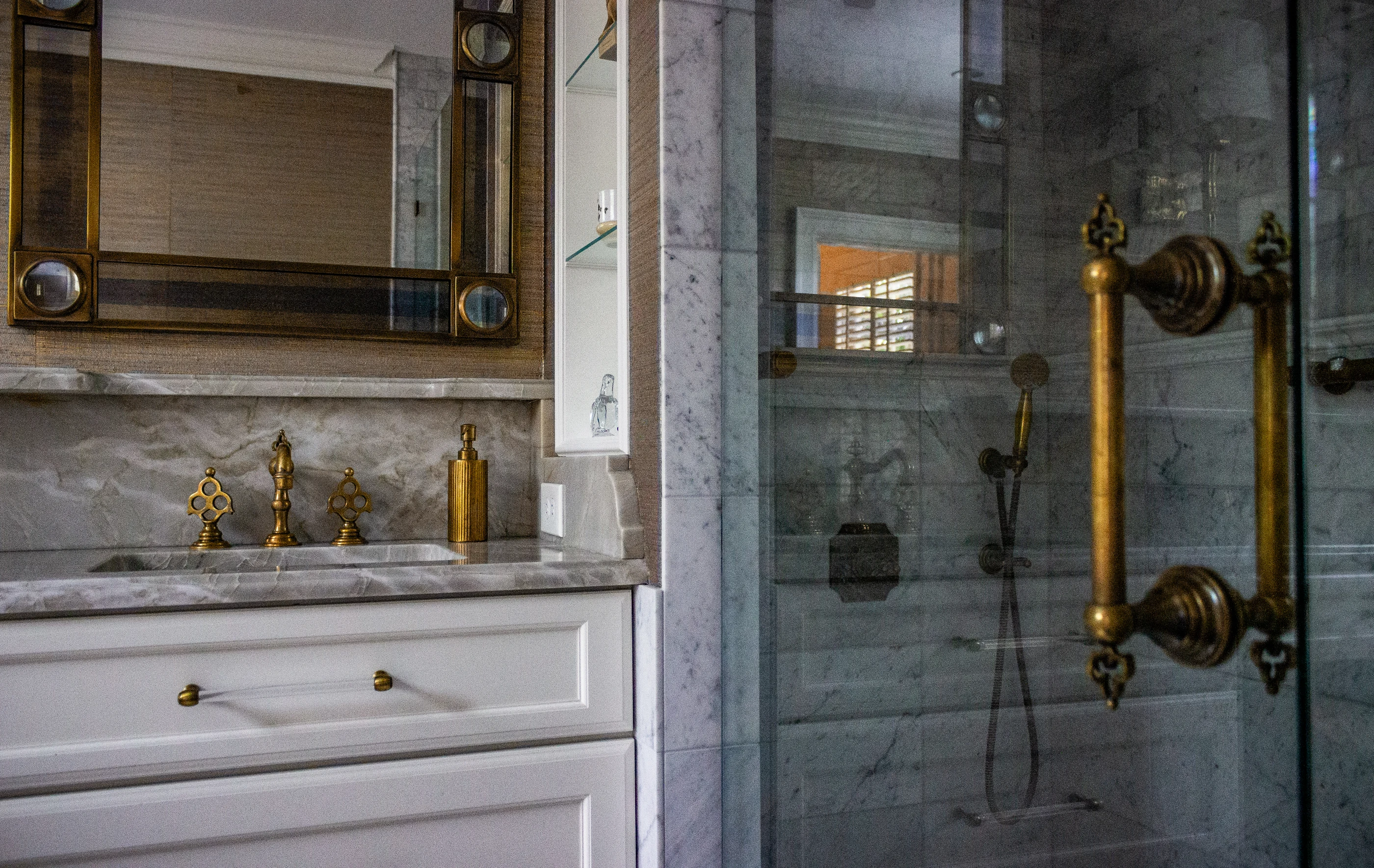 Ashland Park marble bathroom with brass fixtures, a framed mirror and a glass shower.