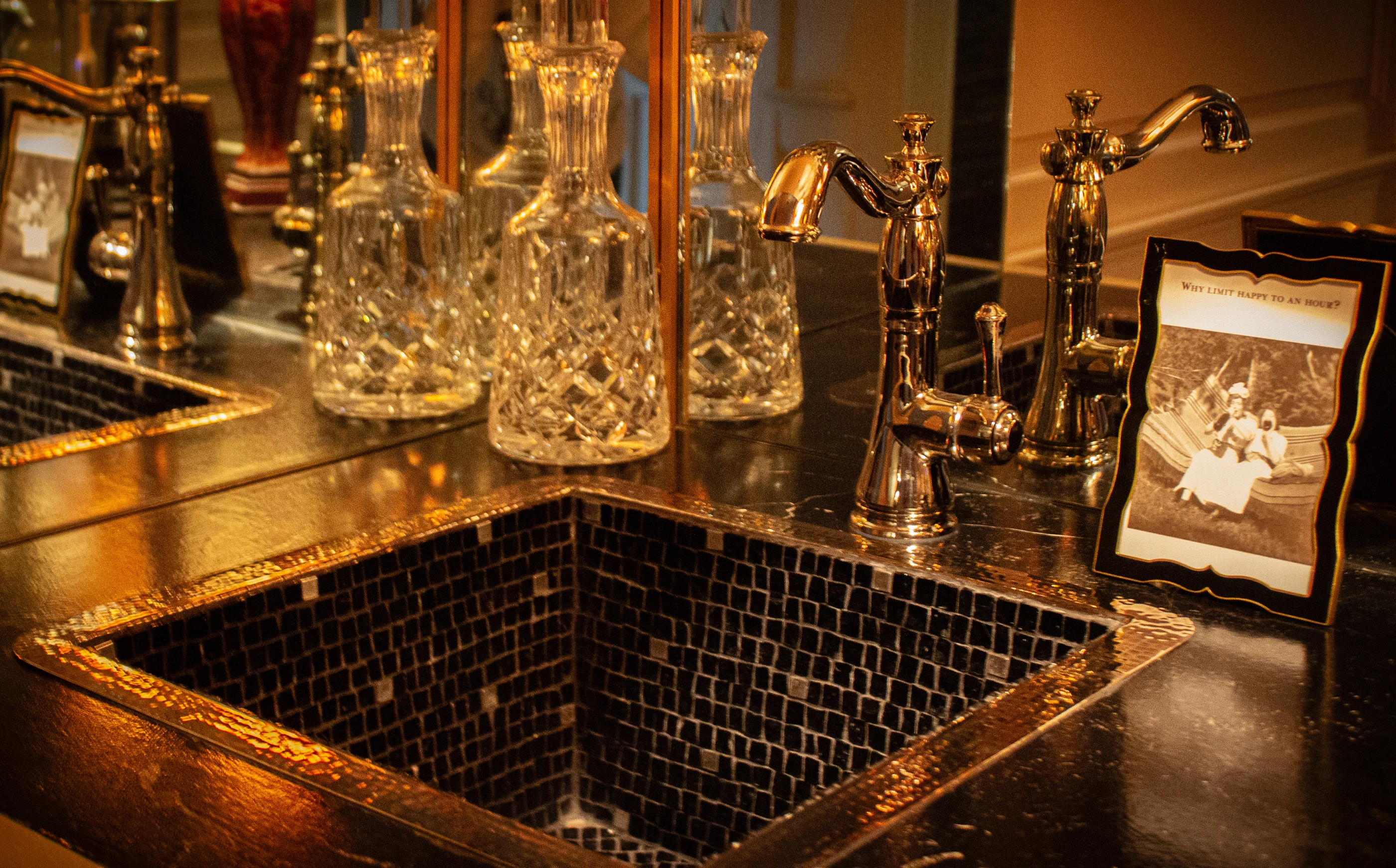 Ashland Park bar detail with crystal decanters, brass fixtures and a mosaic-lined sink.