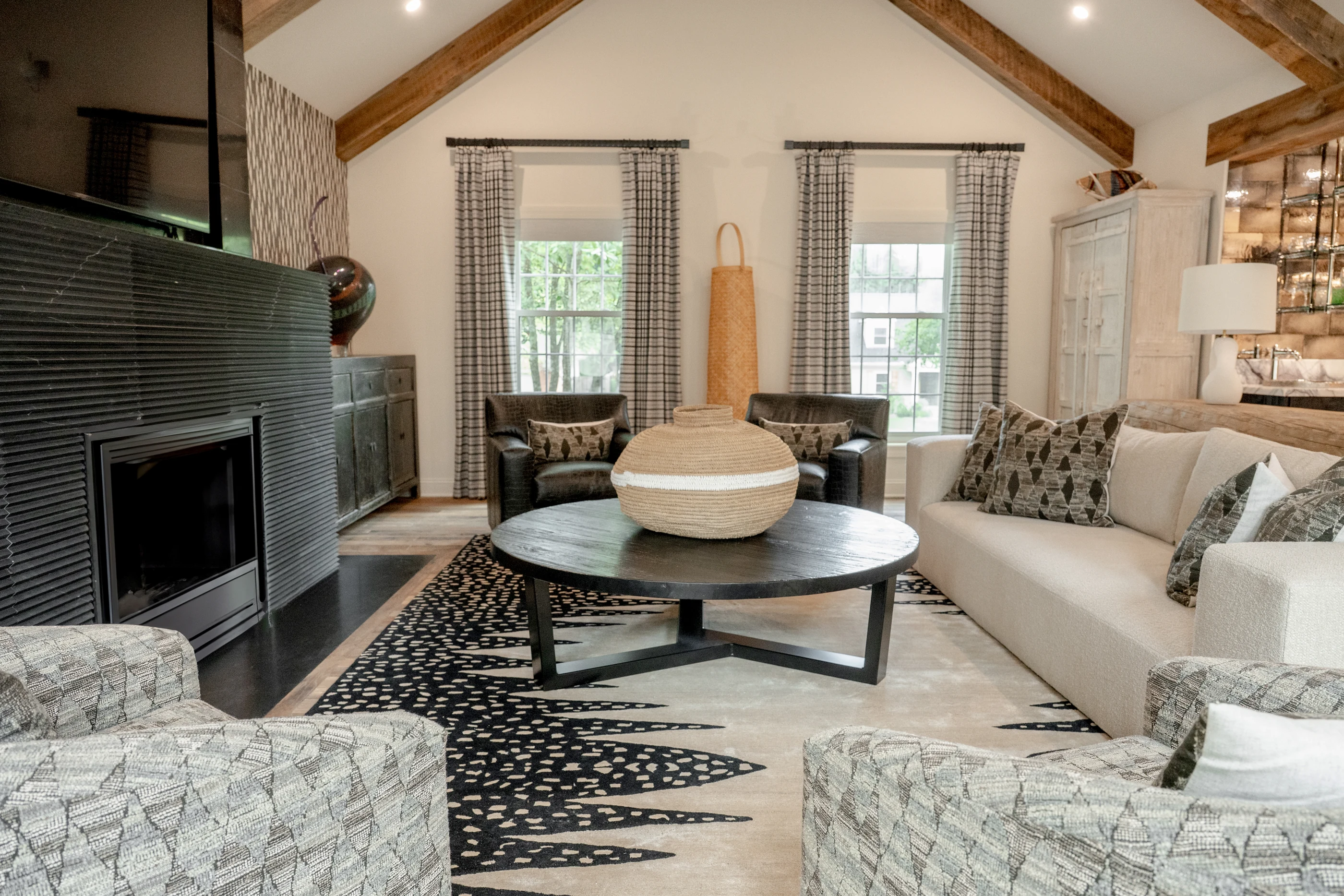 Hart sitting room with timber beams, patterned chairs and a dark fireplace.