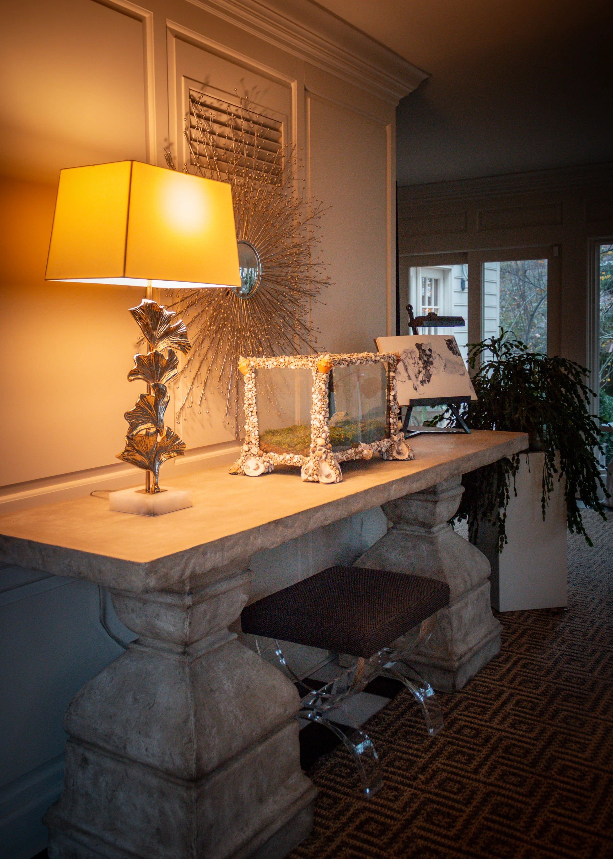 Ashland Park console with a sculptural lamp, framed photographs and upholstered stools.