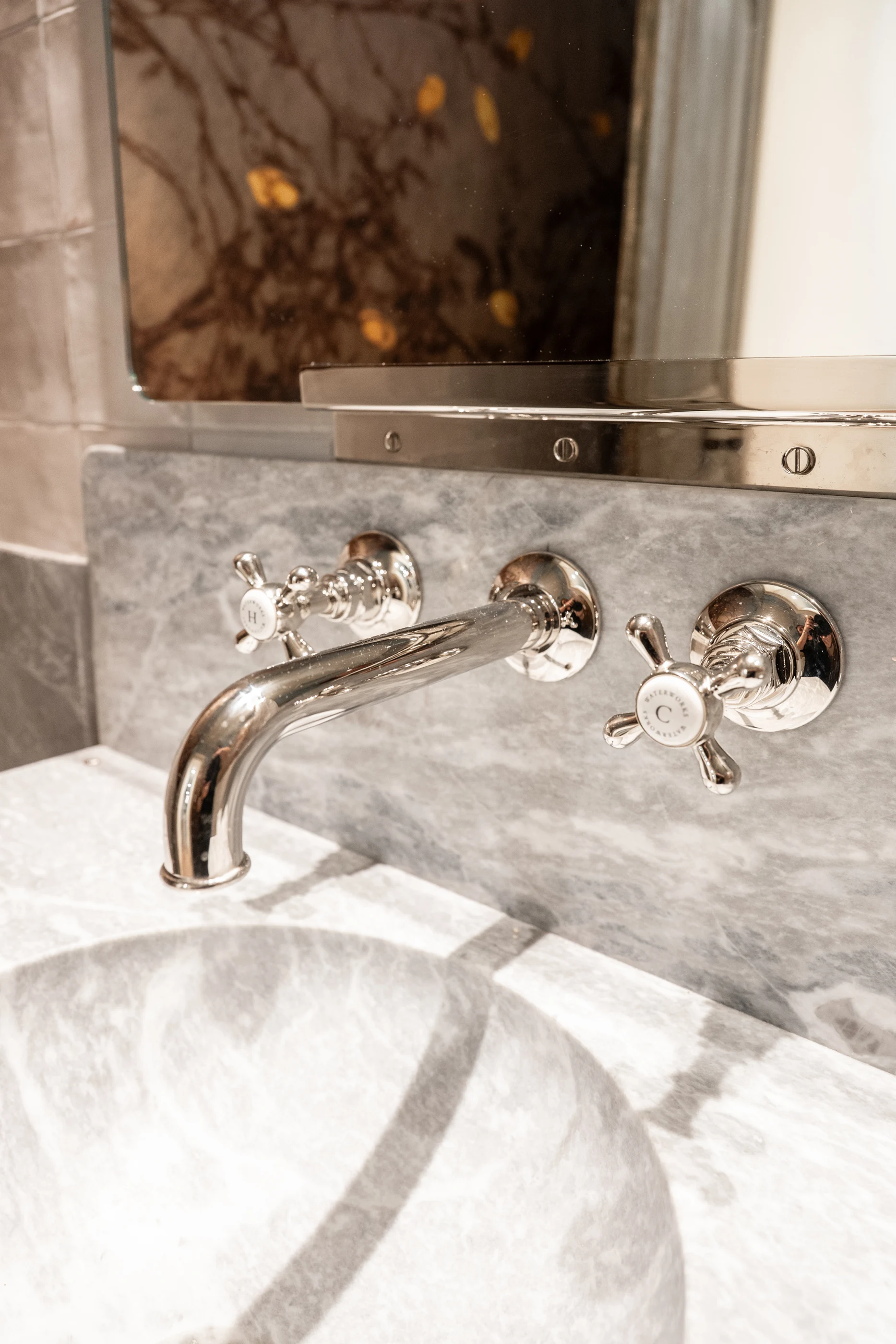 Hart polished fixture detail against the sculptural marble vanity.