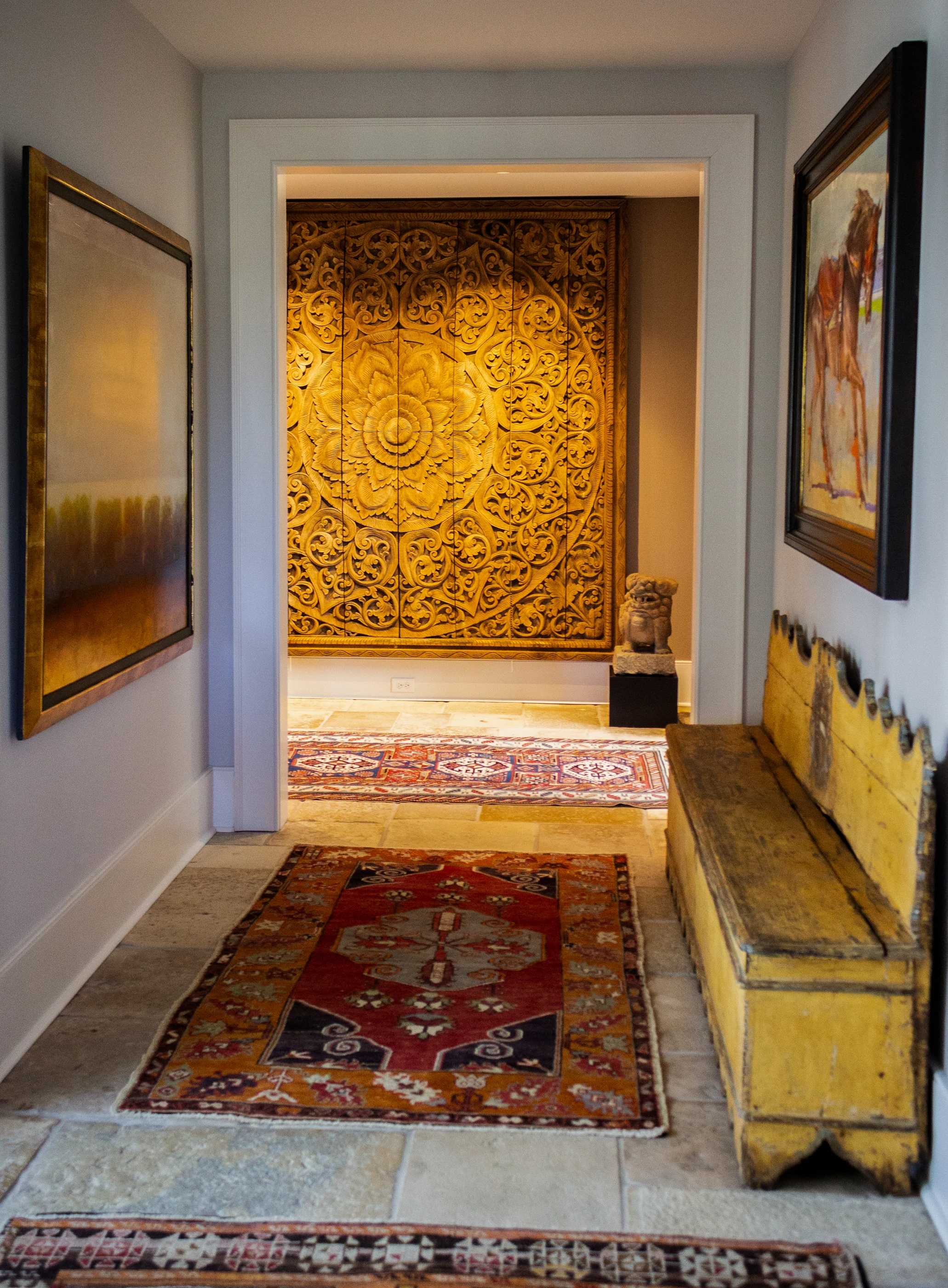Art-lined hallway and carved wall panel at Equestrian Estate.