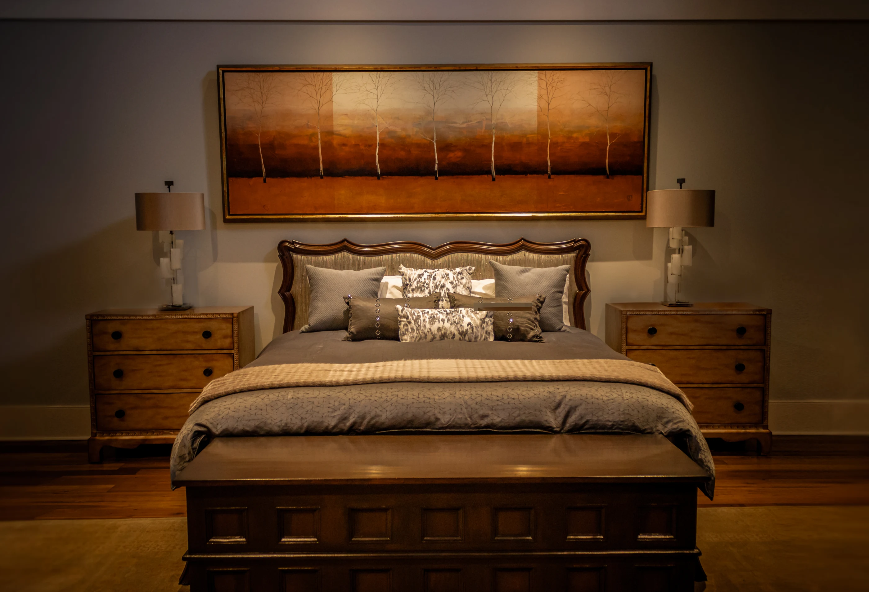 Bedroom with an upholstered bed and warm landscape painting at Equestrian Estate.