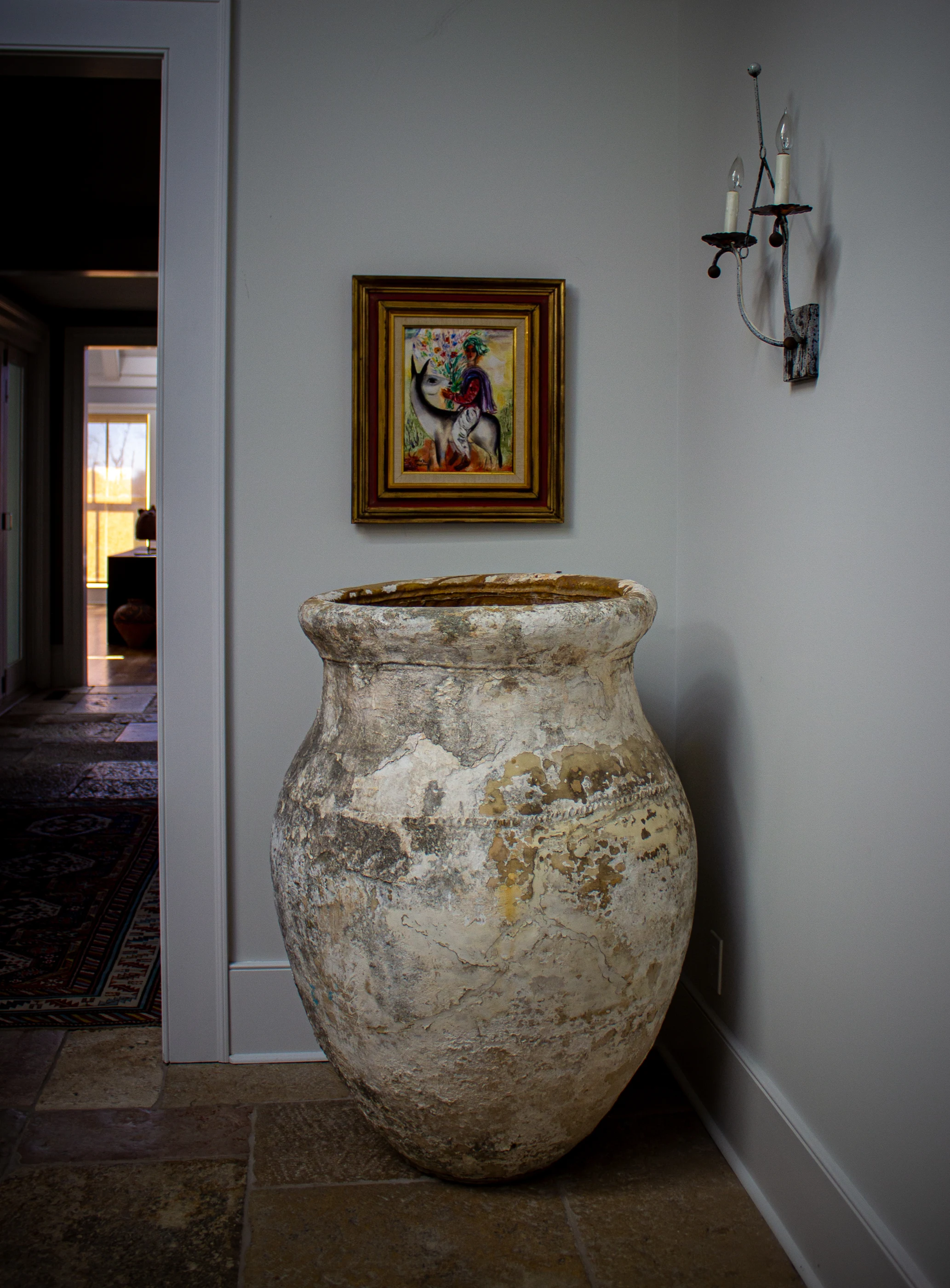 Oversized antique vessel beneath artwork at Equestrian Estate.
