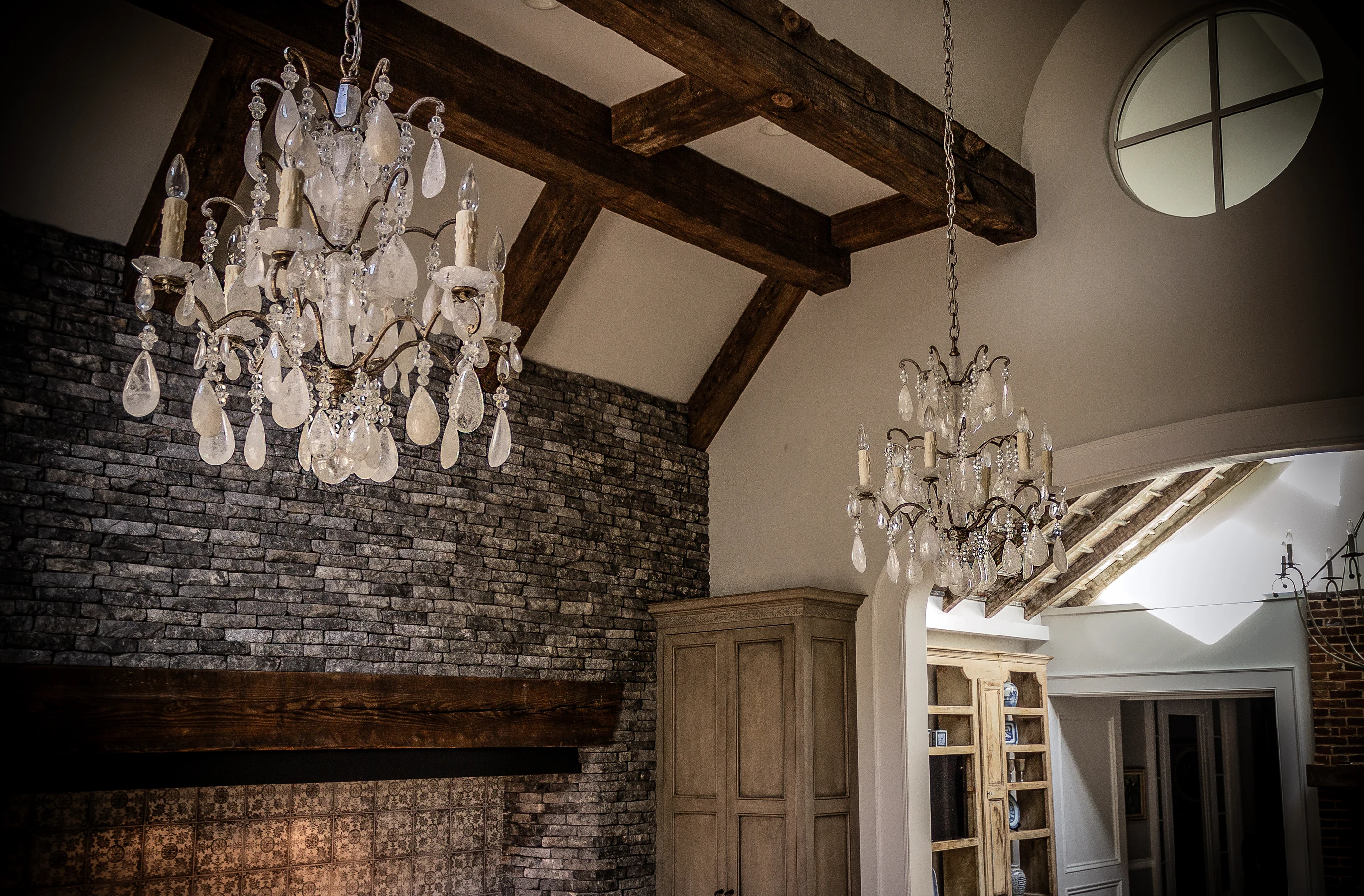 Crystal chandeliers beside a stone range hood at Equestrian Estate.