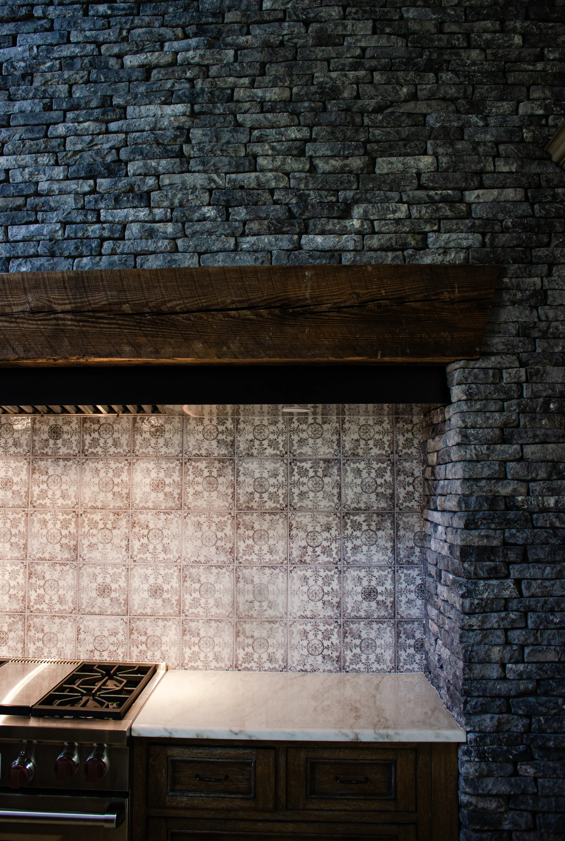 Textured stone range hood and patterned backsplash at Equestrian Estate.