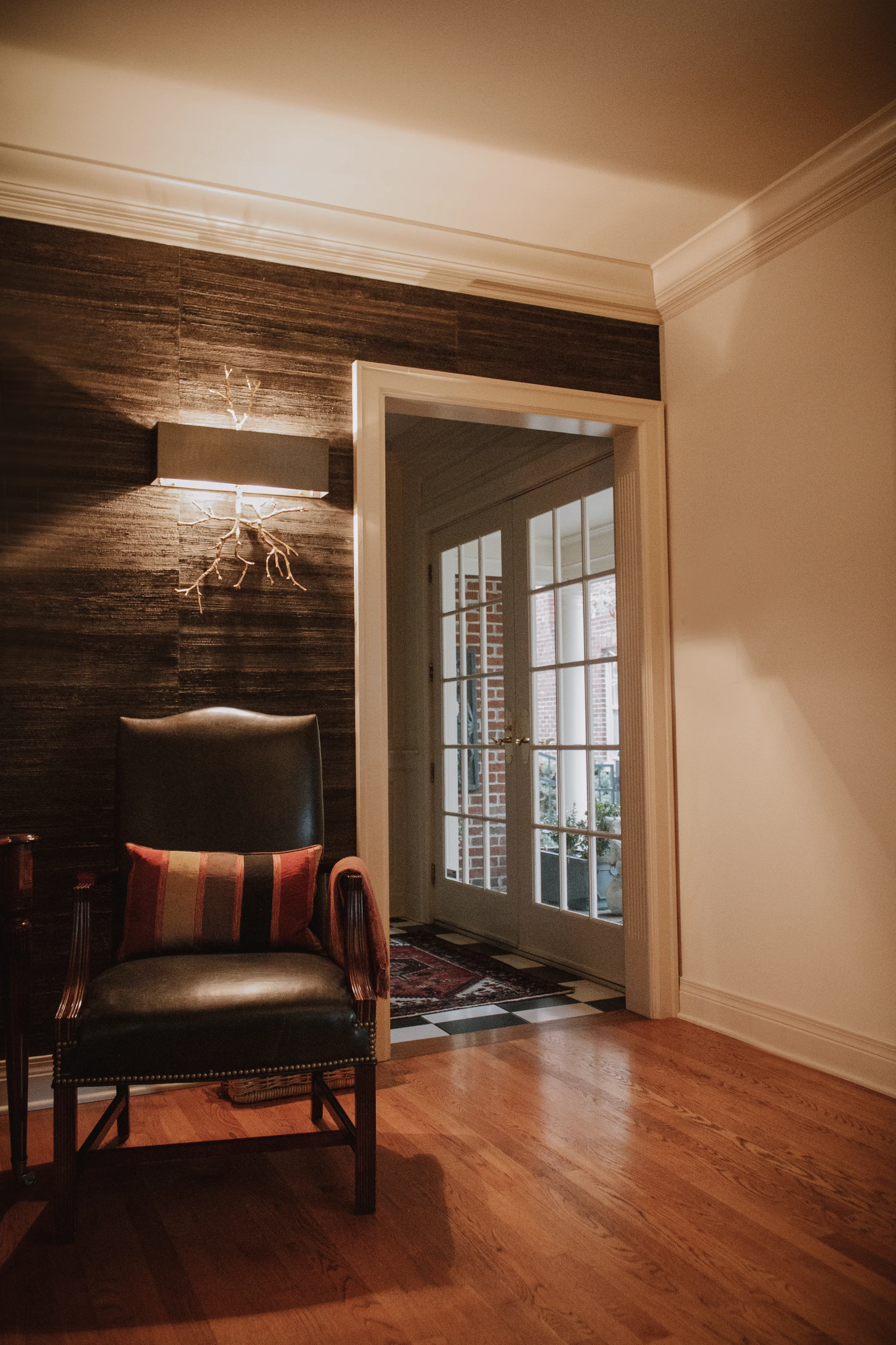 Wing chair and textured wallcovering beside a glazed doorway at Ashland Park.