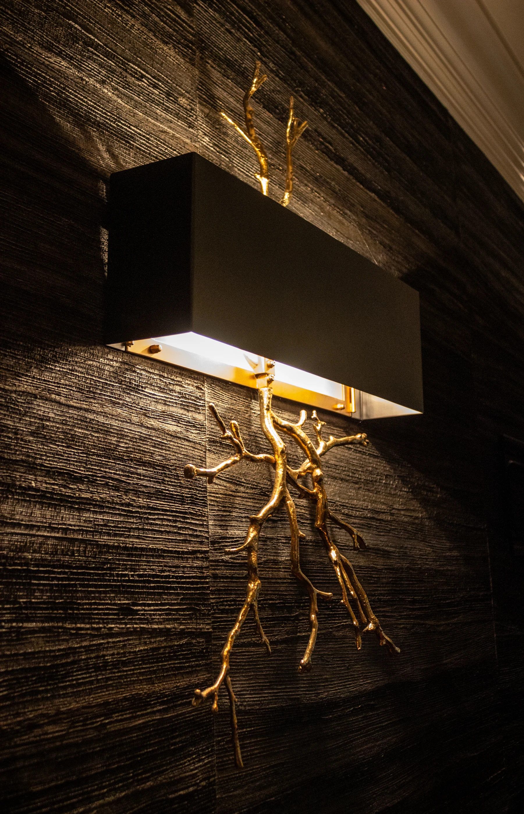 Sculptural brass wall light against textured wallcovering at Ashland Park.