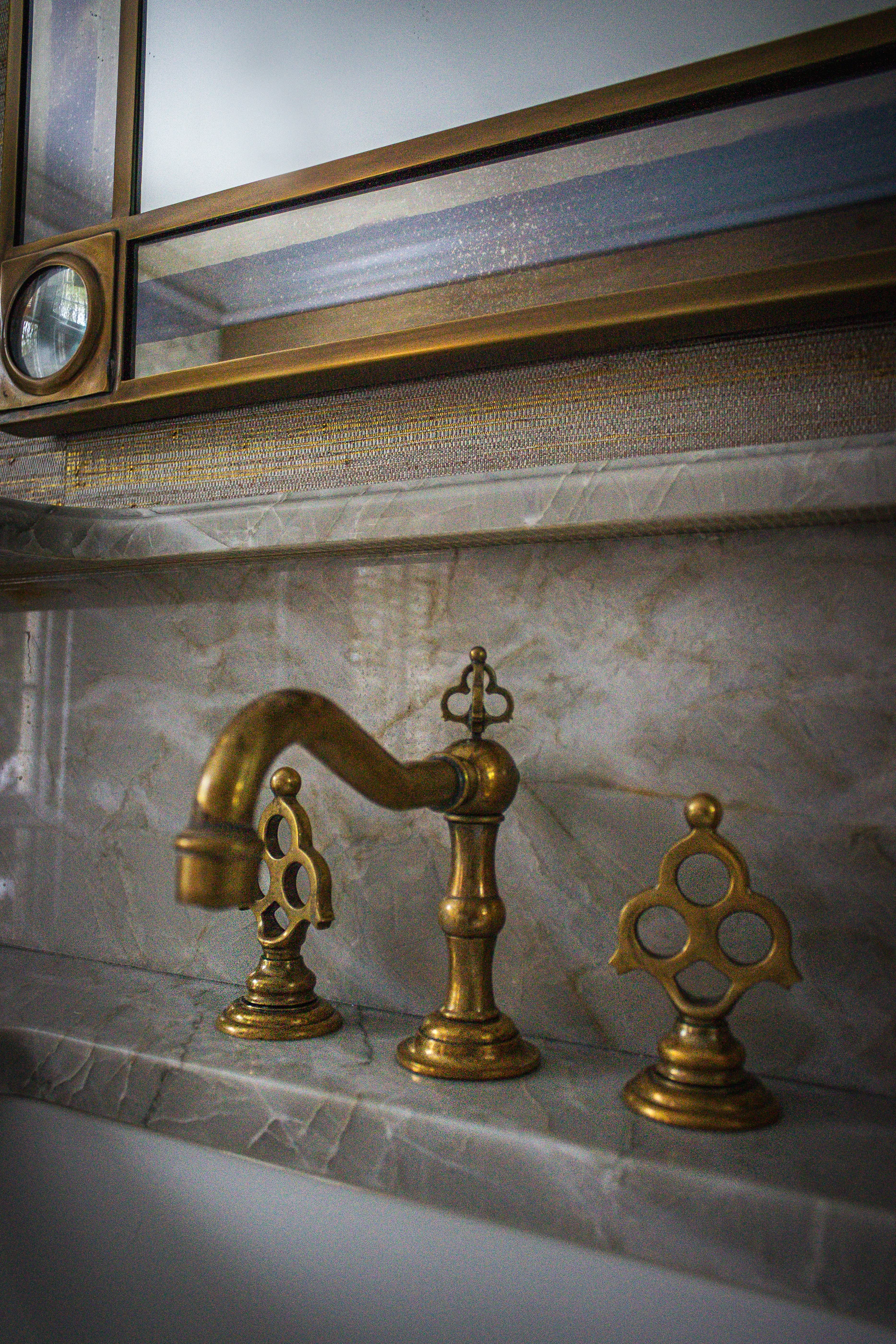 Aged brass faucet against richly veined marble at Ashland Park.