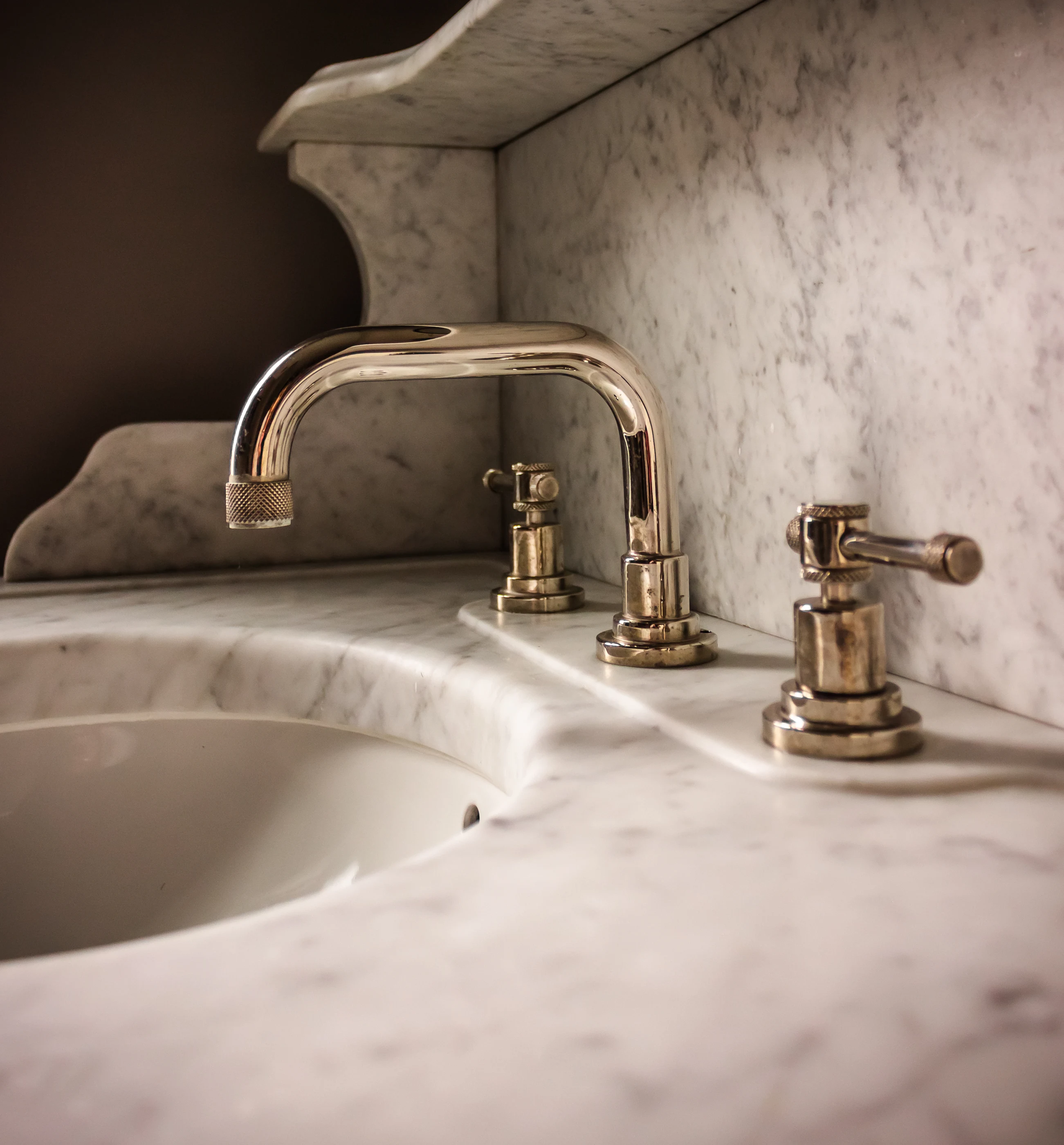 Polished faucet against the sculpted stone backsplash at Chevy Chase.