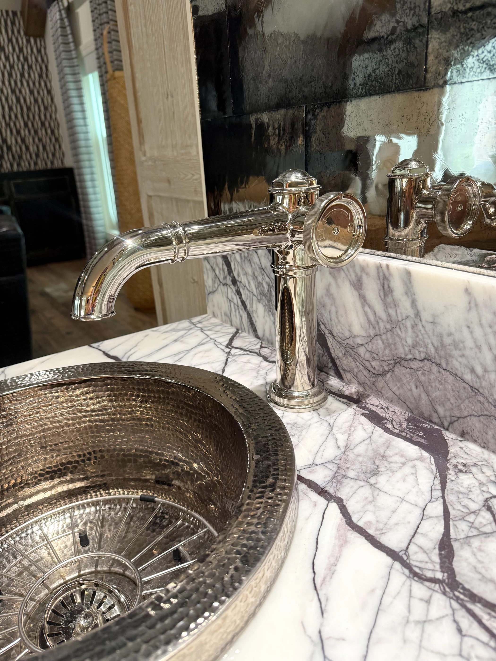 Polished metal faucet and hammered sink set into veined stone at Hart.