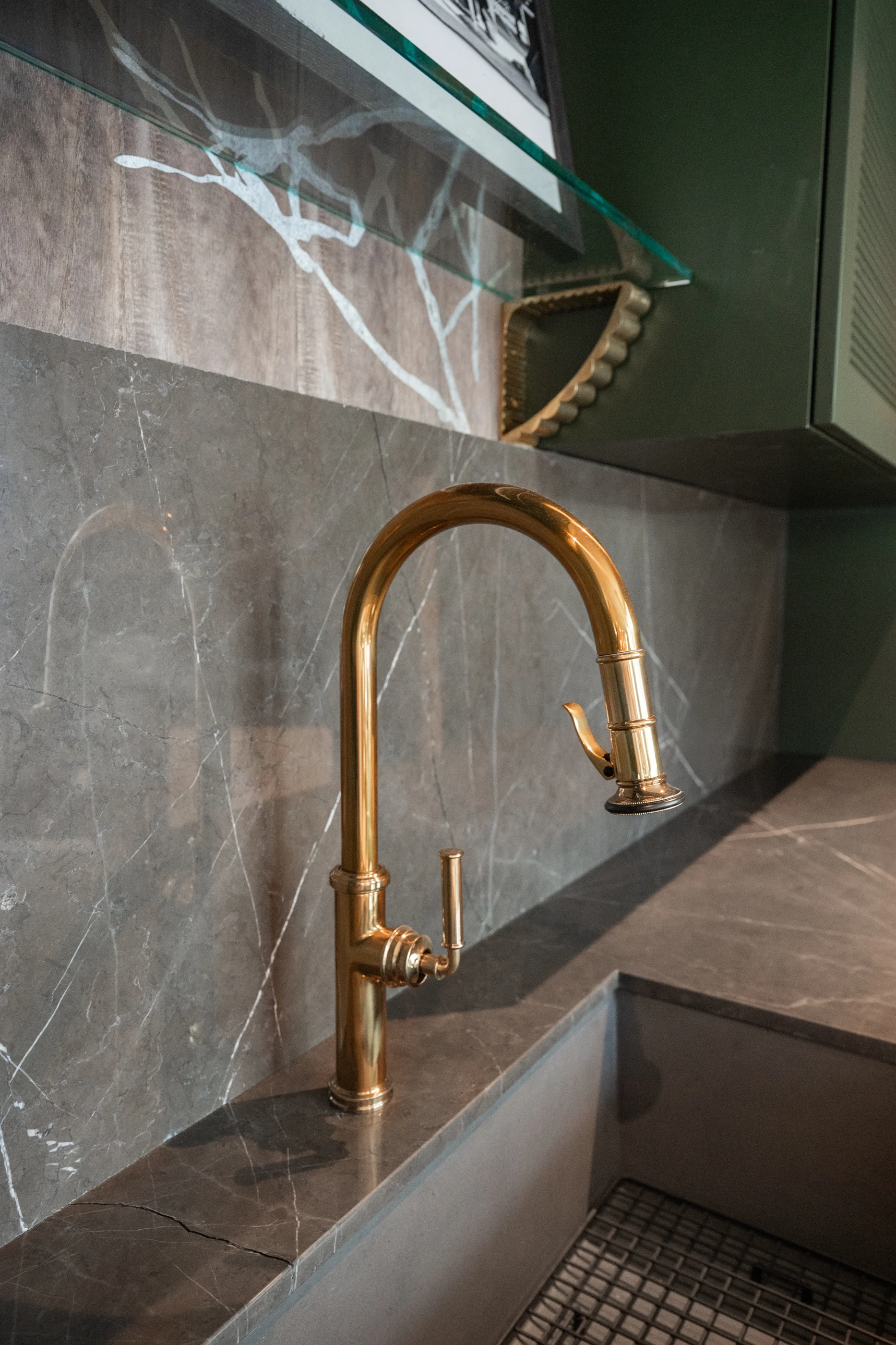 Brass faucet against soft gray stone in the Cabinet & Stone Lab showroom.