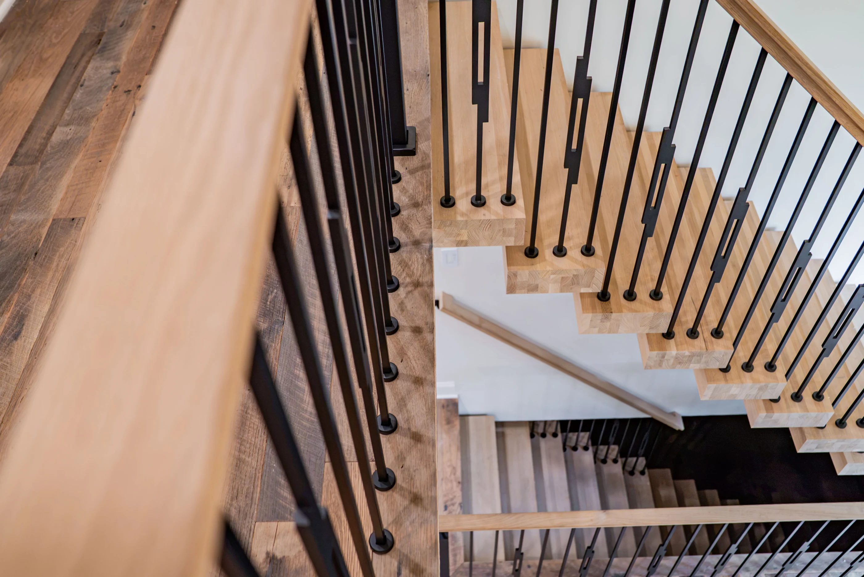 Oak stair treads and geometric dark metal balusters at Hart.