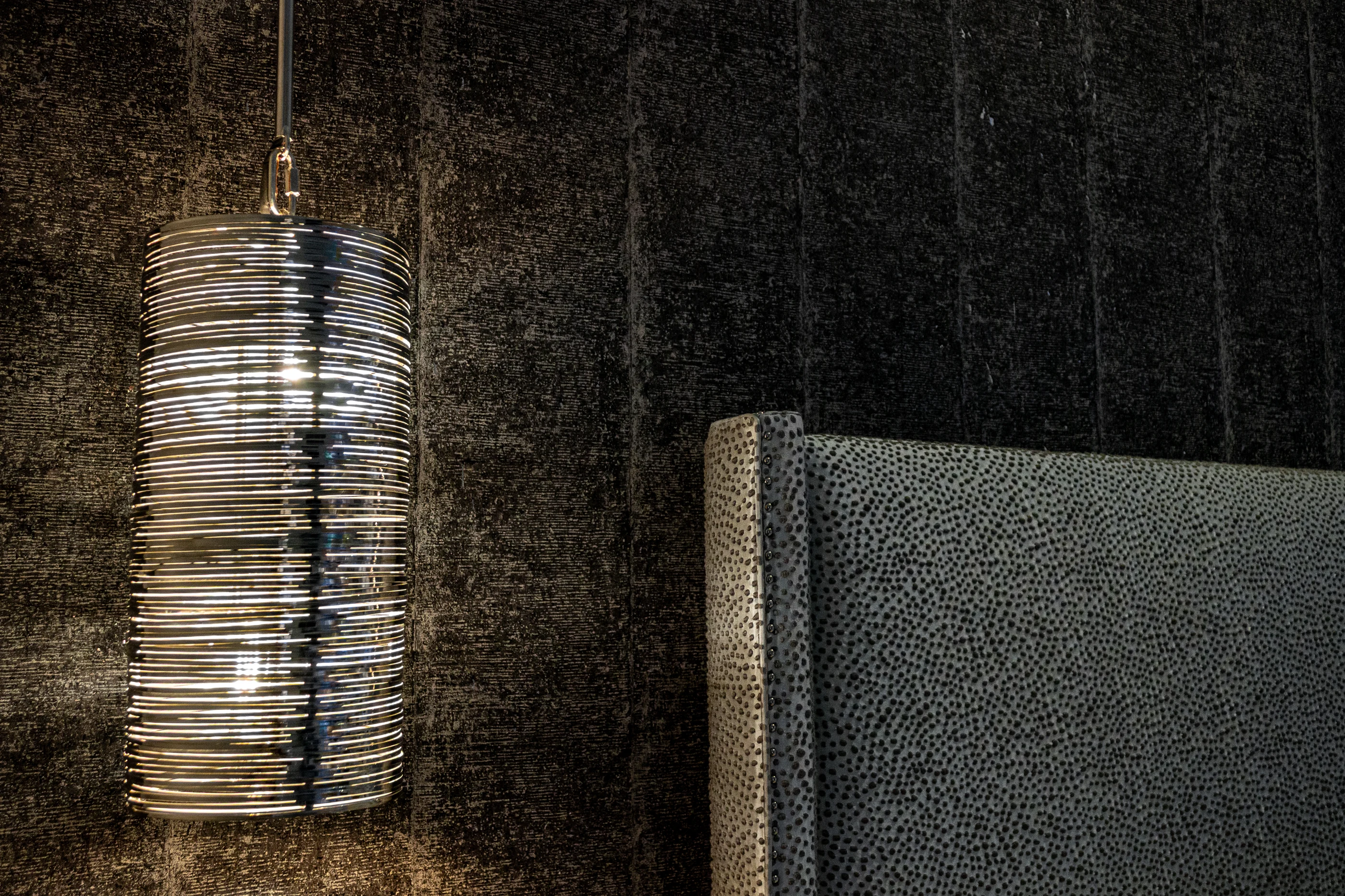 Glass bedside pendant against textured wallcovering at Urban Mod.
