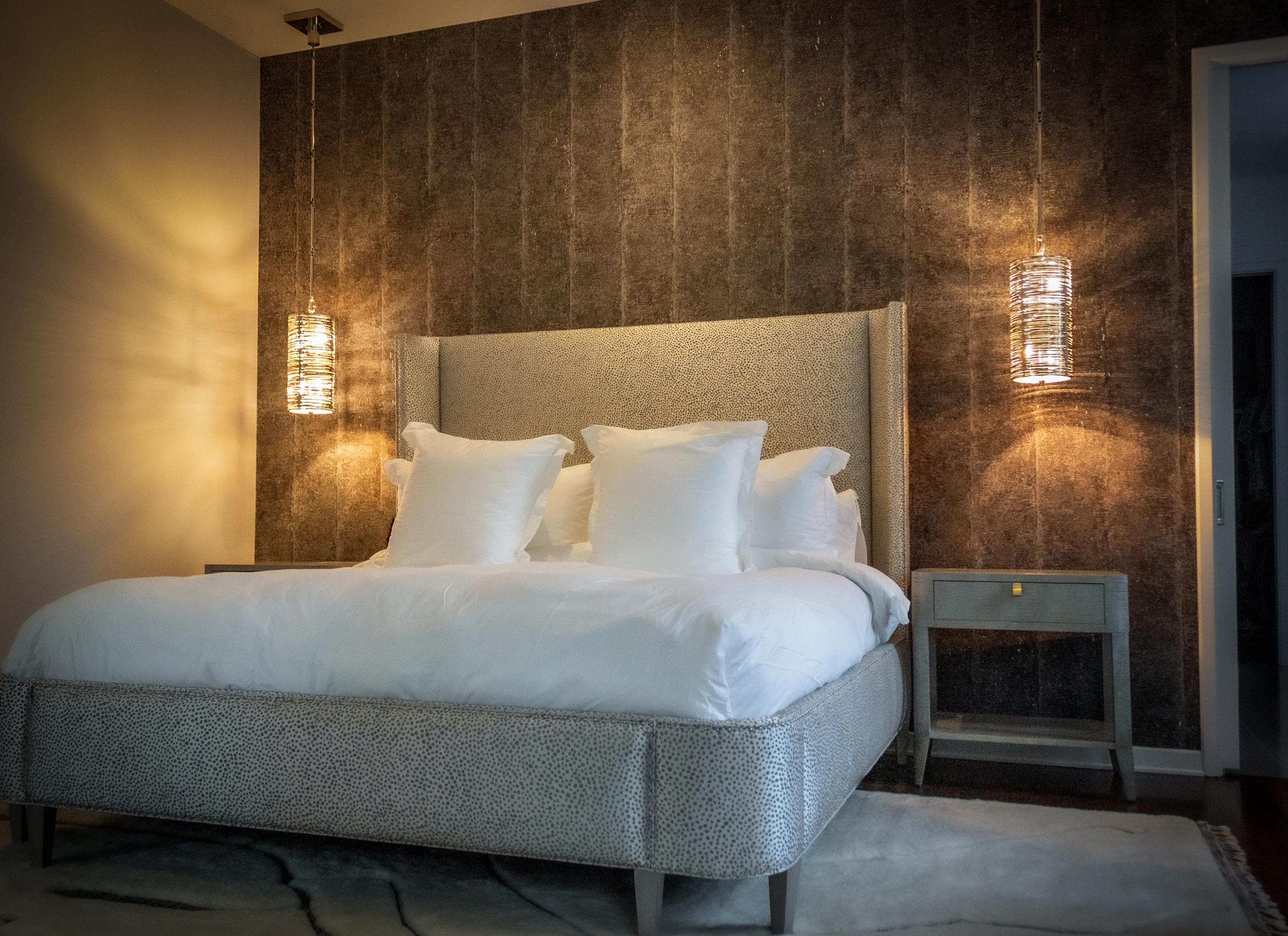Upholstered bed framed by glass pendants at Urban Mod.