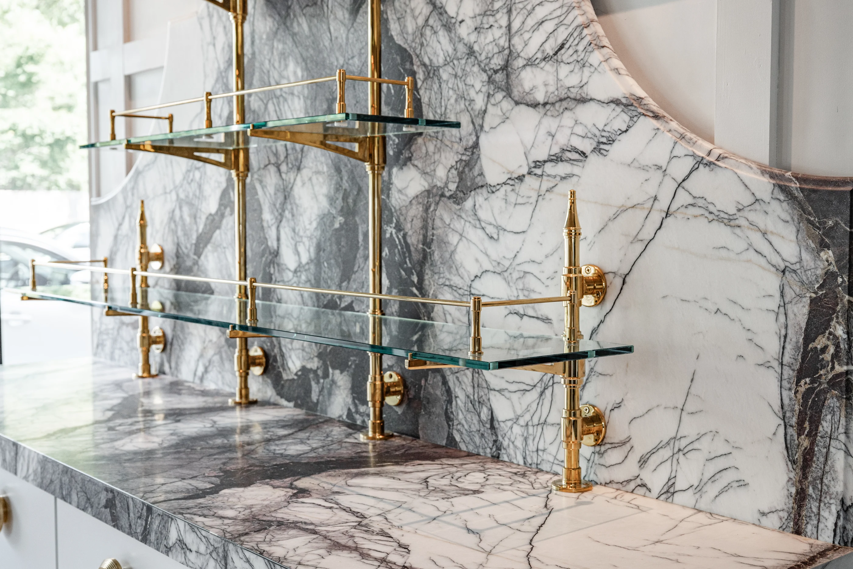 Expressive stone with brass and glass shelving in the Cabinet & Stone Lab showroom.