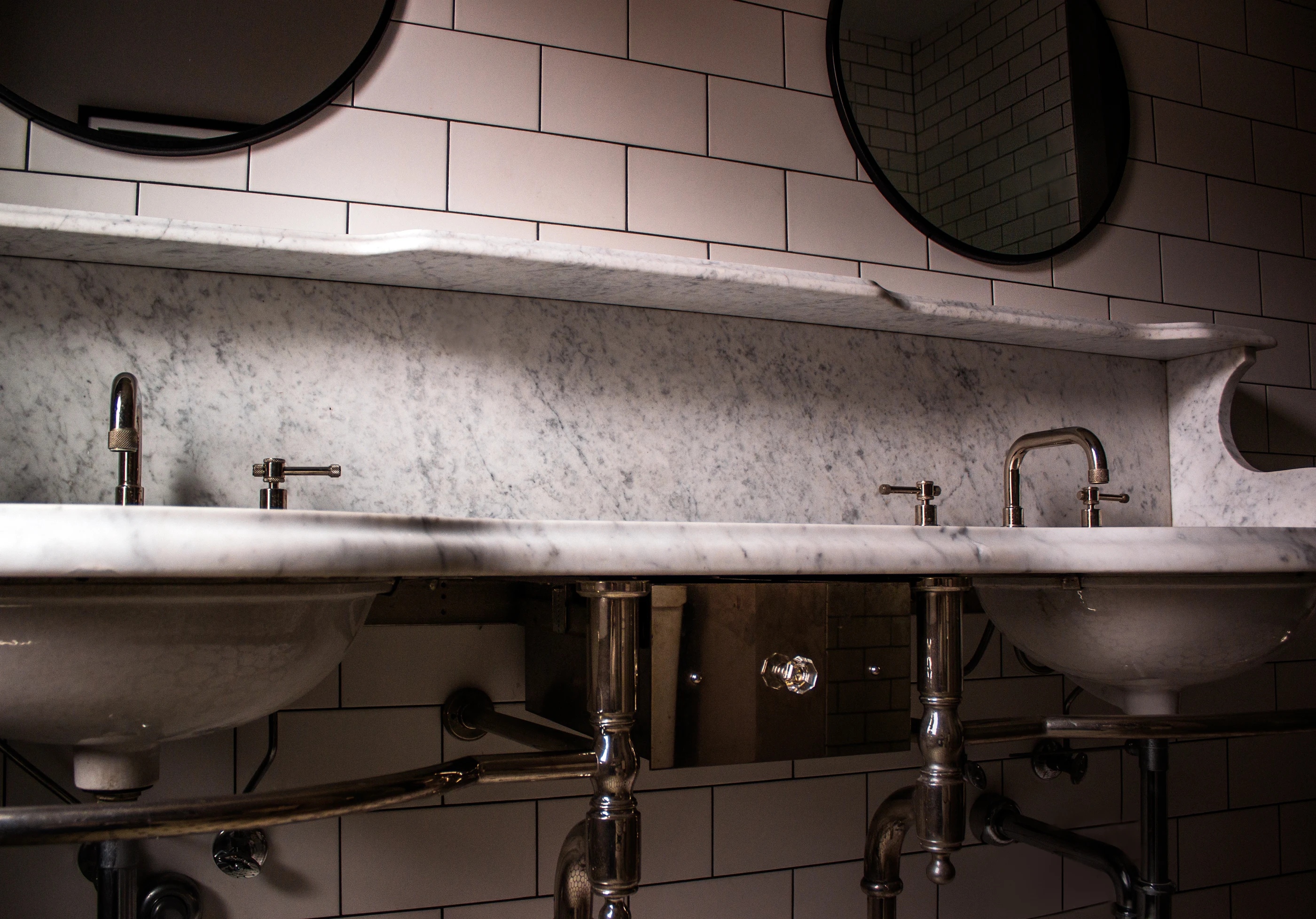 Double vanity with curved stone backsplash at Chevy Chase.