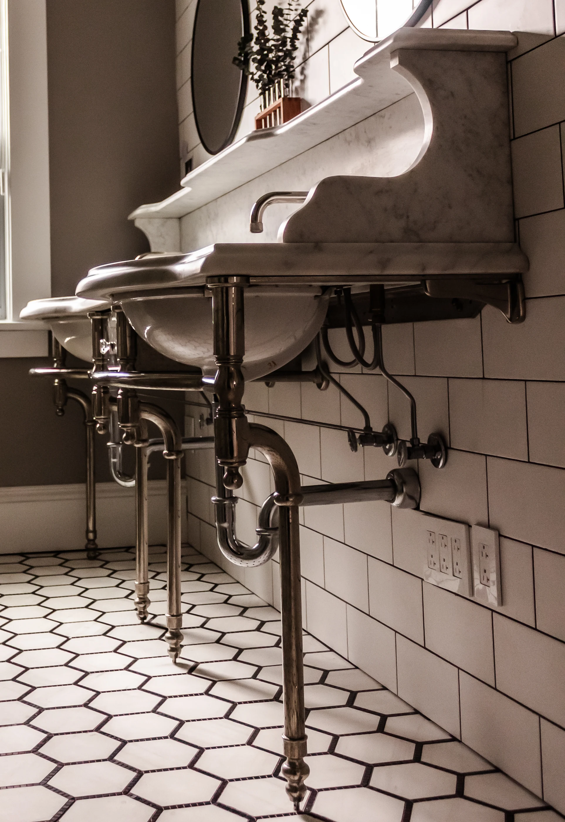 Polished metal vanity legs above hexagonal floor tile at Chevy Chase.