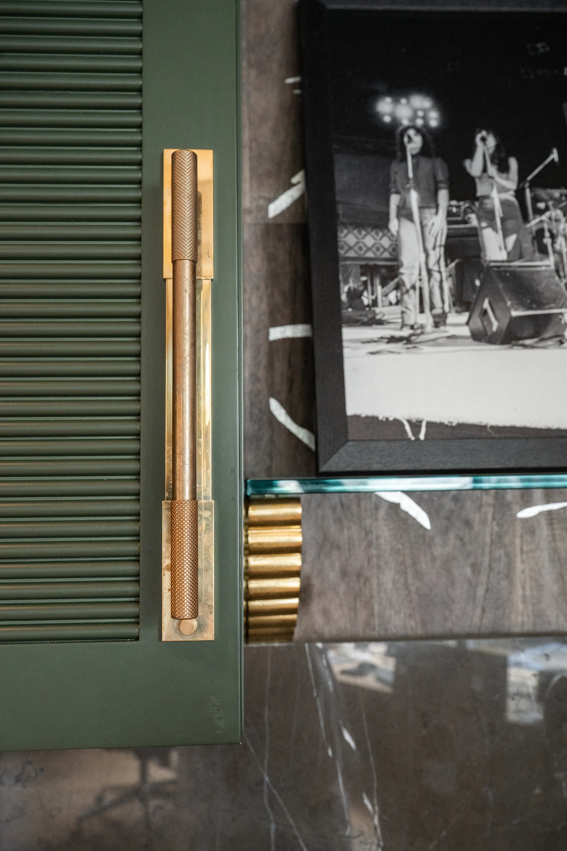 Brass cabinet pull beside display shelving in the Cabinet & Stone Lab showroom.
