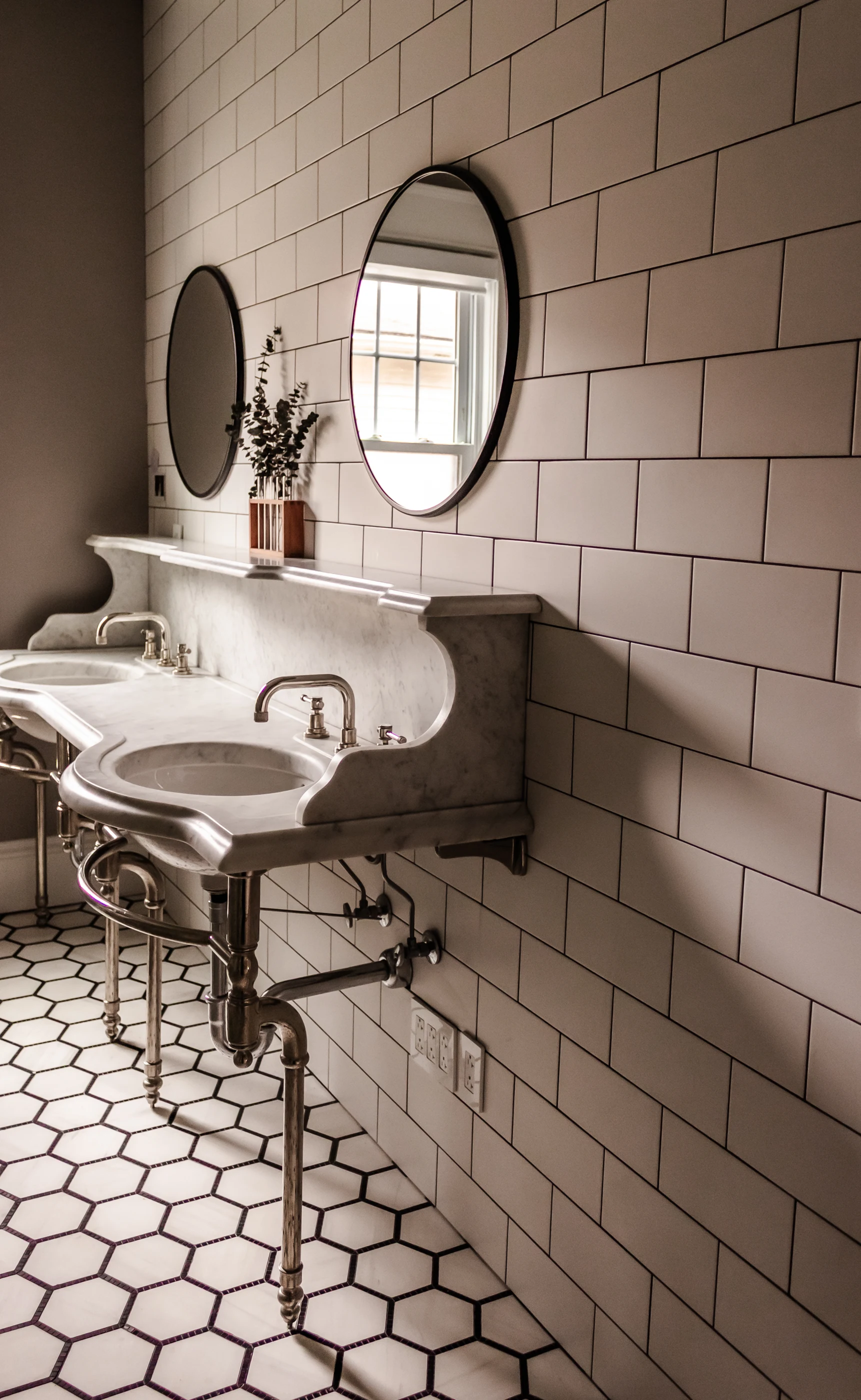 Sculptural double vanity against pale wall tile at Chevy Chase.