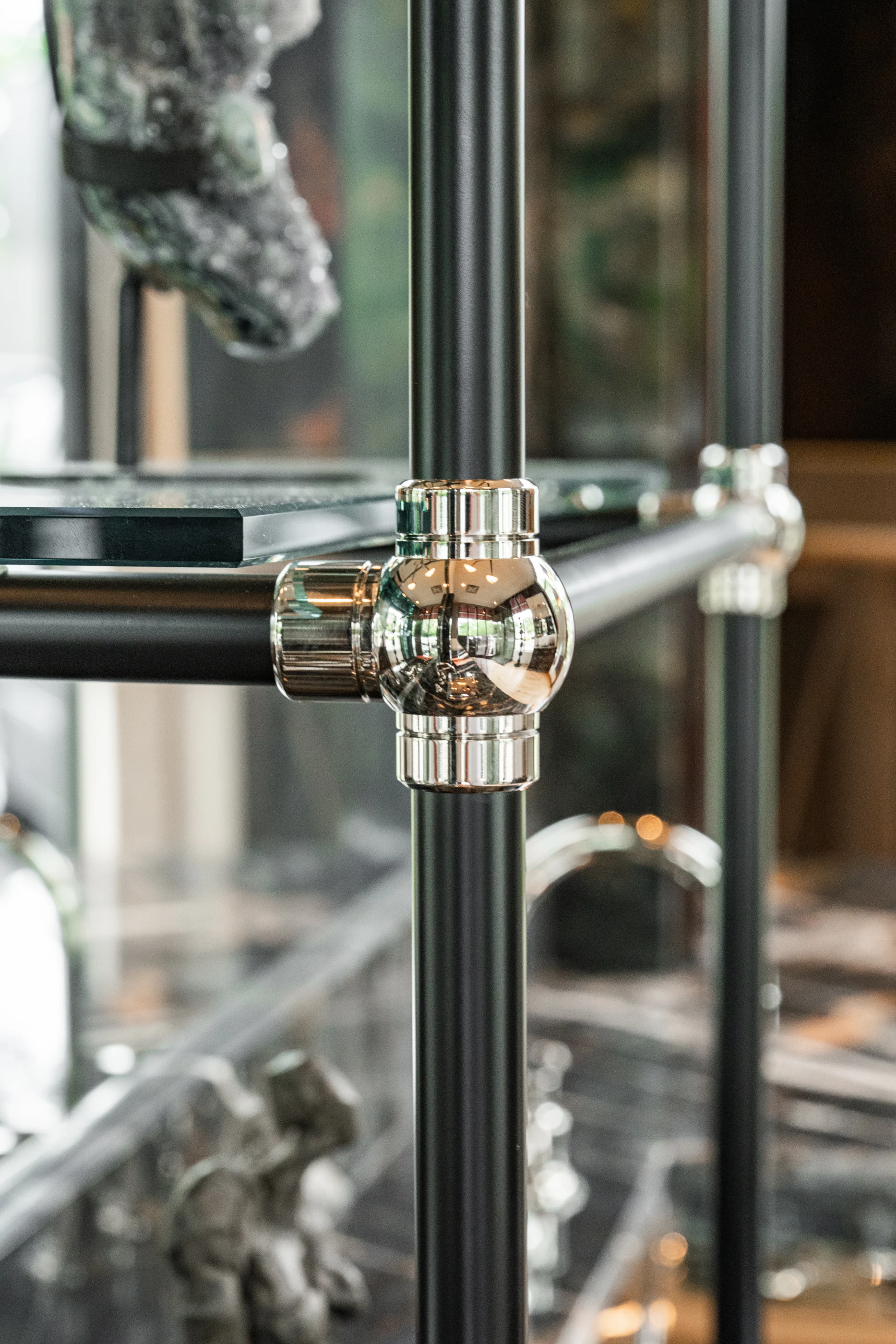 Polished metal and glass shelf connection in the Cabinet & Stone Lab showroom.