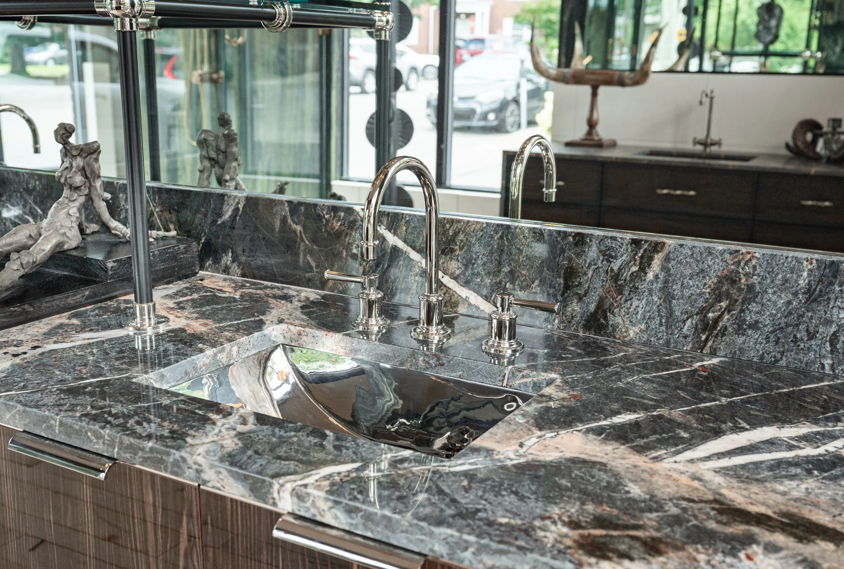 Polished faucet and sink in expressive dark stone in the Cabinet & Stone Lab showroom.