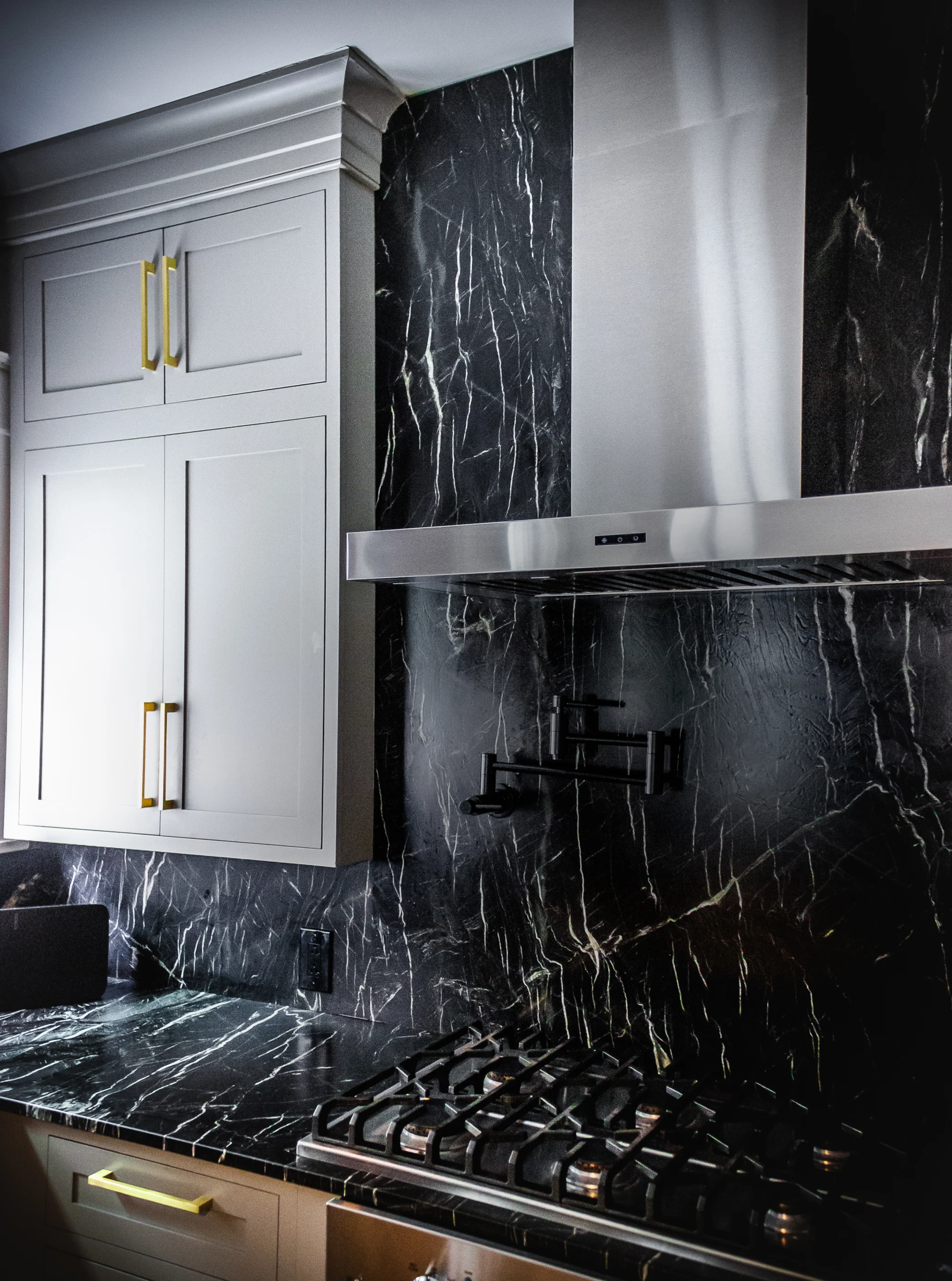 Range hood framed by dark veined stone at Chevy Chase.