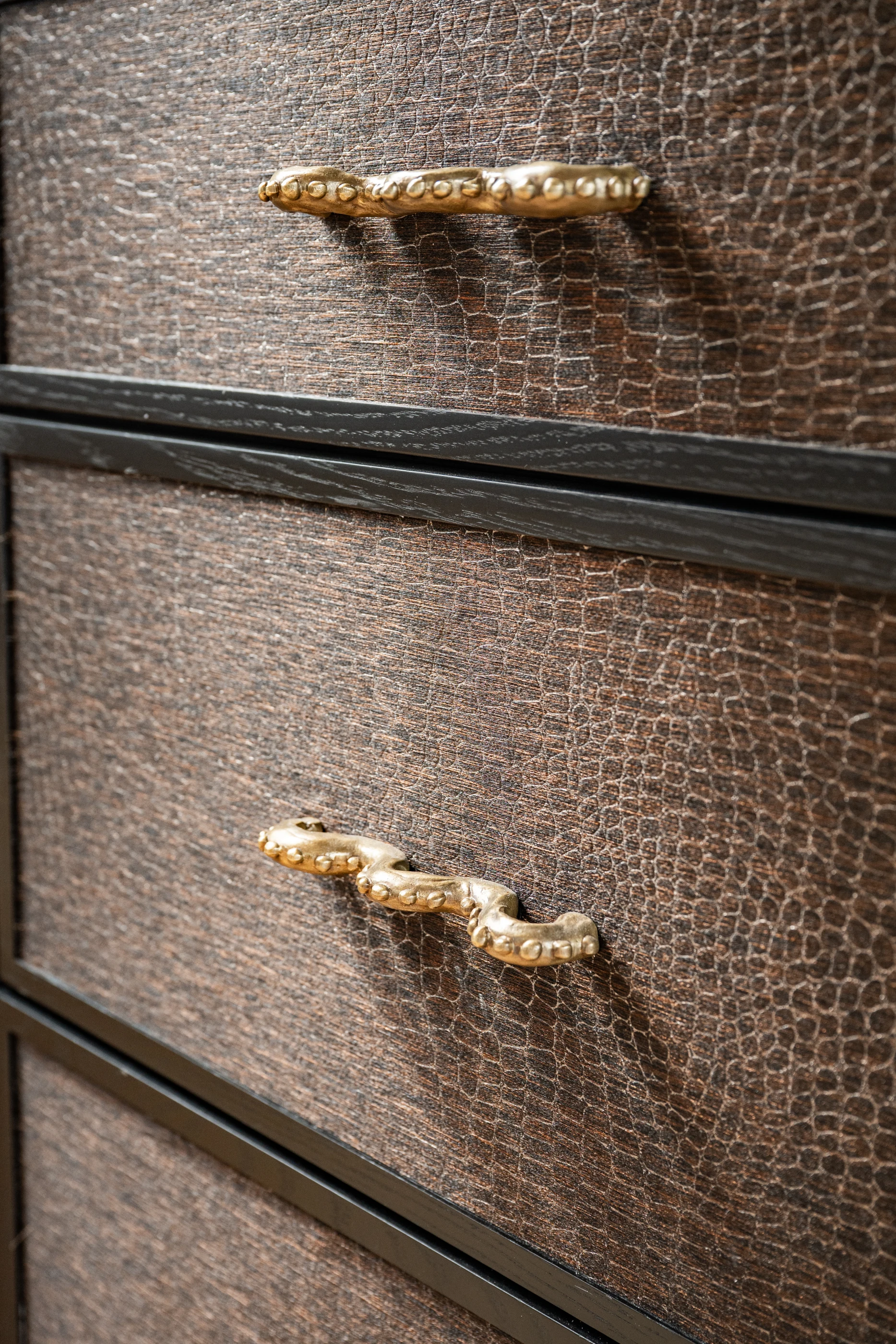 Textured cabinet fronts and sculptural brass pulls in the Cabinet & Stone Lab showroom.
