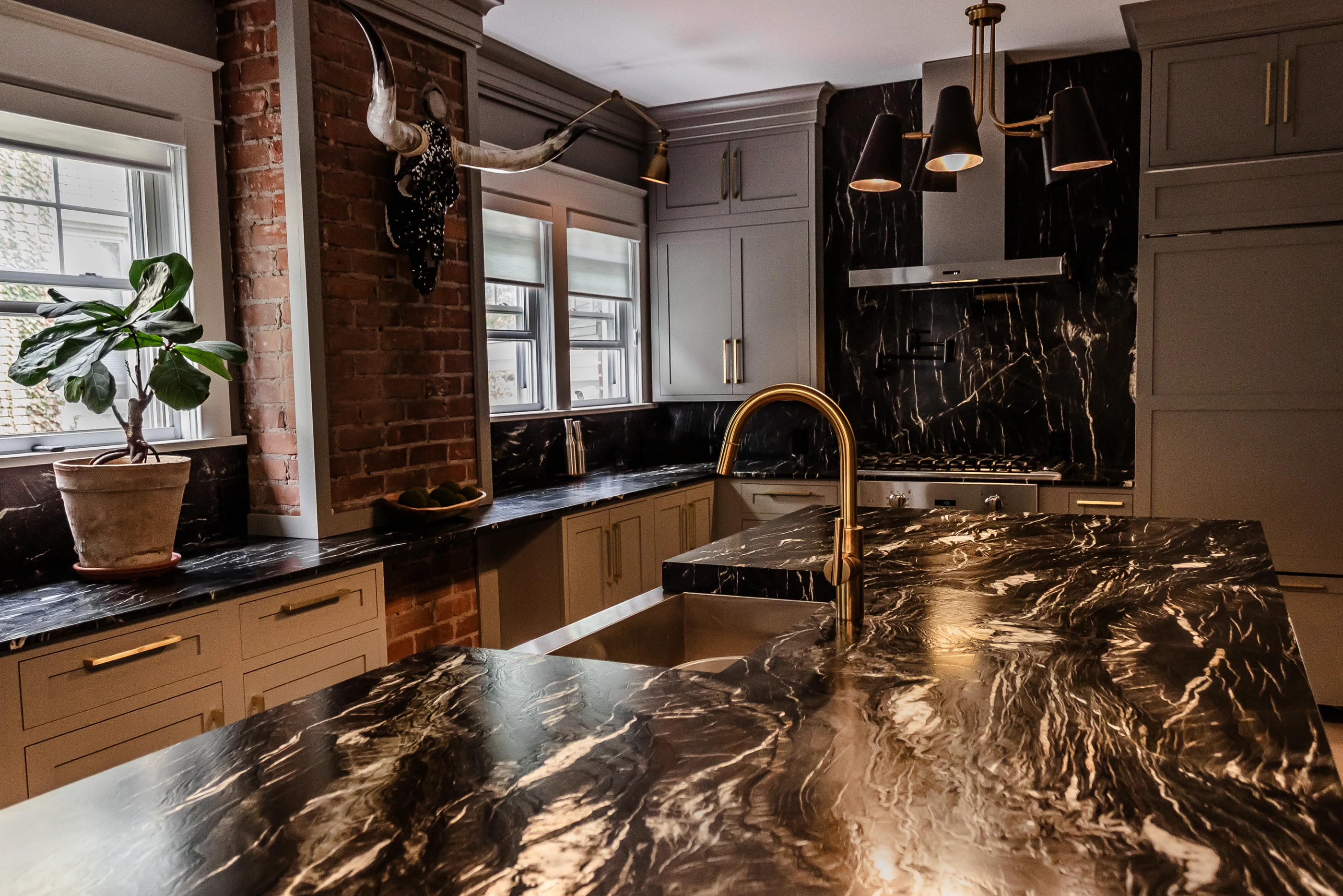 Dark stone countertop, brass faucet and brick accents at Chevy Chase.