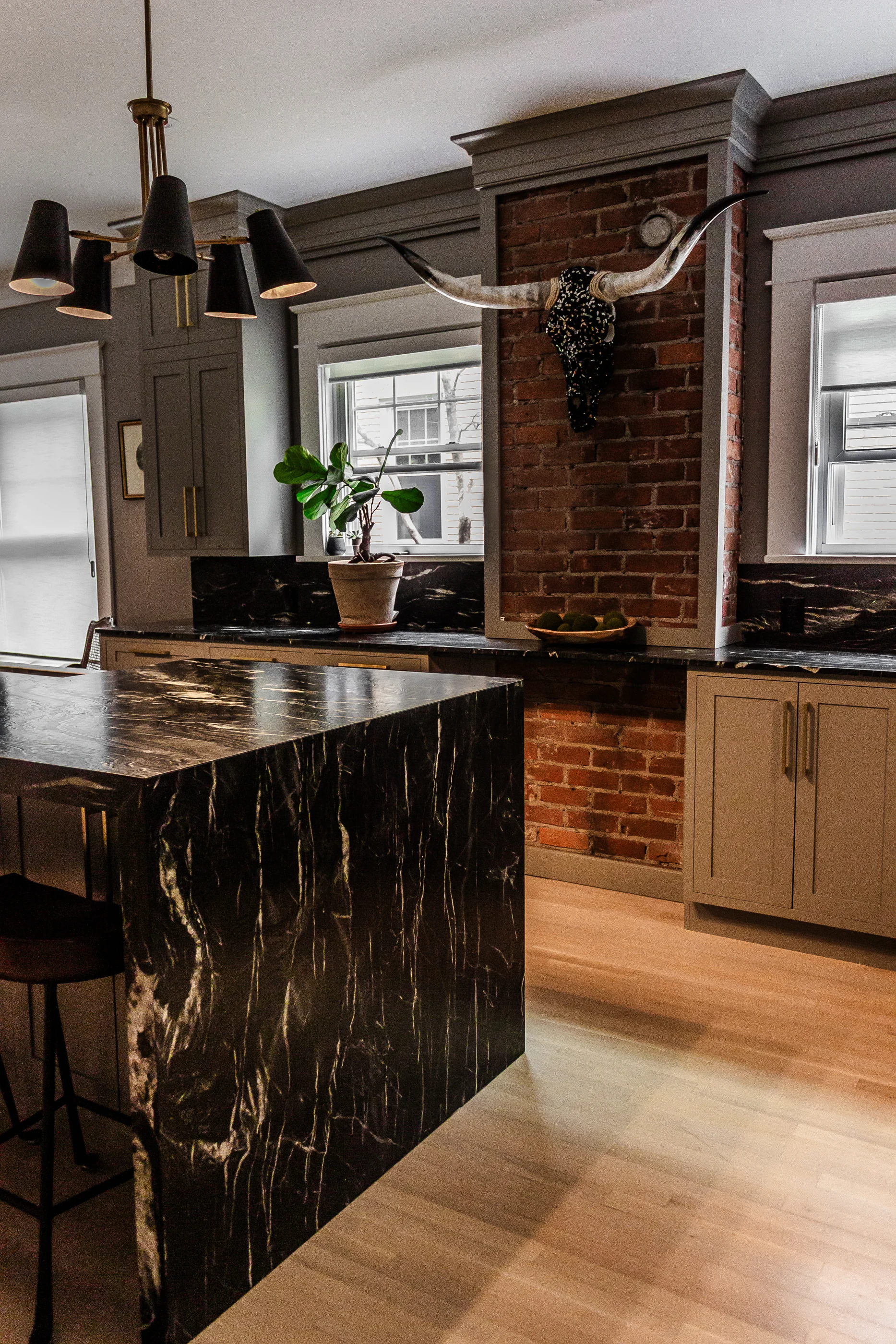 Stone island beside exposed brick and pale cabinetry at Chevy Chase.