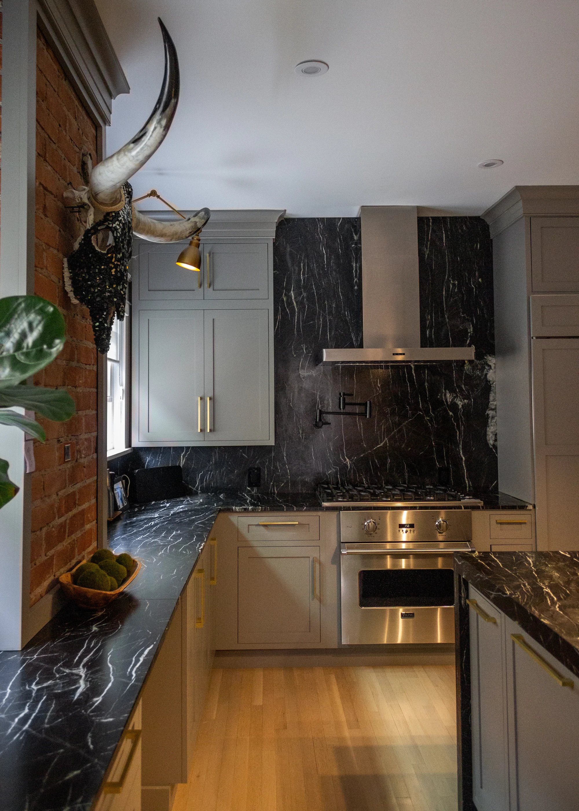 Kitchen range and cabinetry beside exposed brick at Chevy Chase.