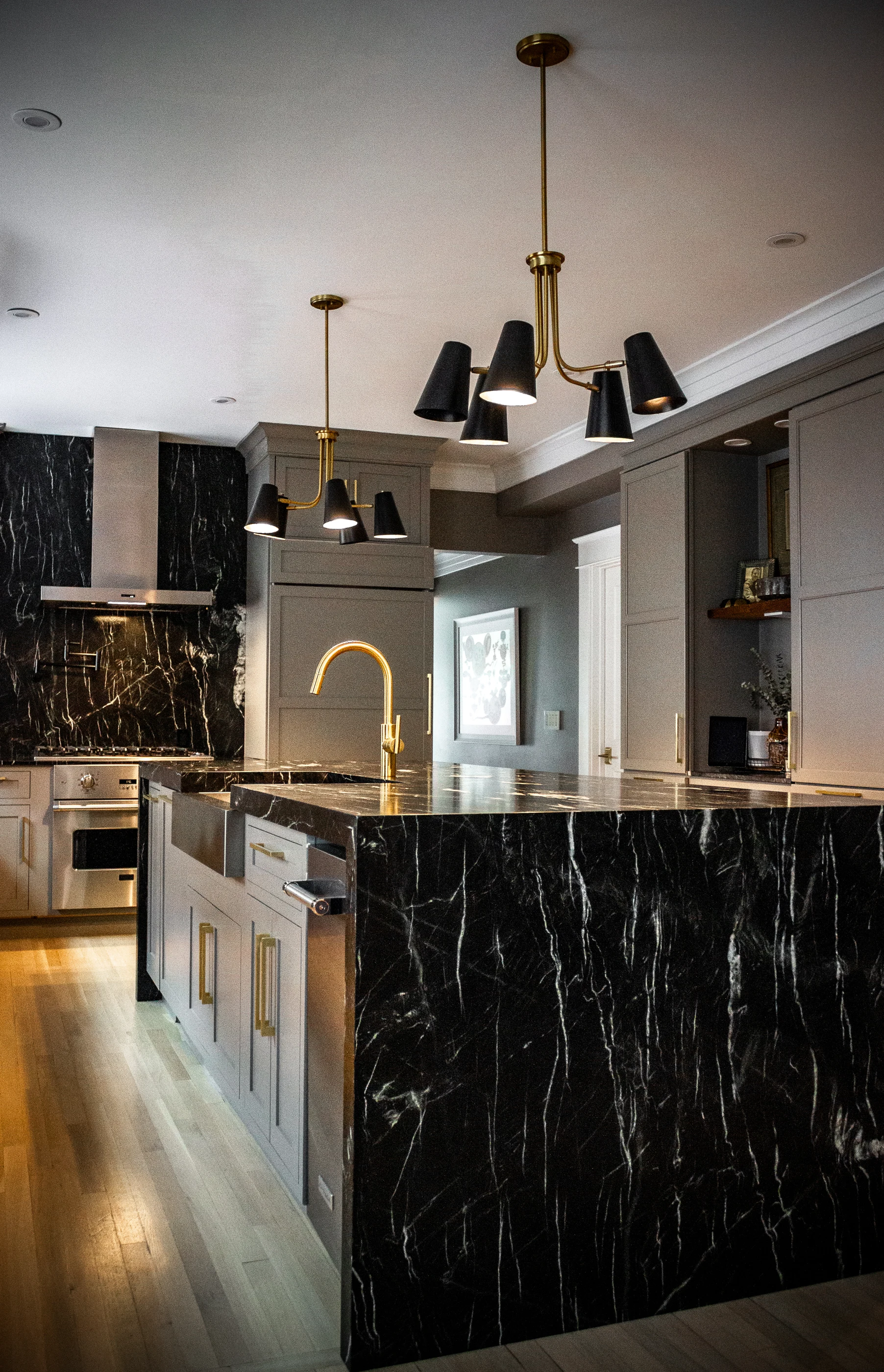 Dark stone kitchen island beneath sculptural pendants at Chevy Chase.