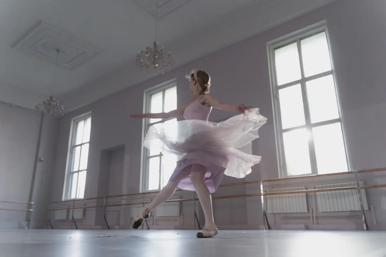 Ballet dancer spinning in a bright studio with large windows.