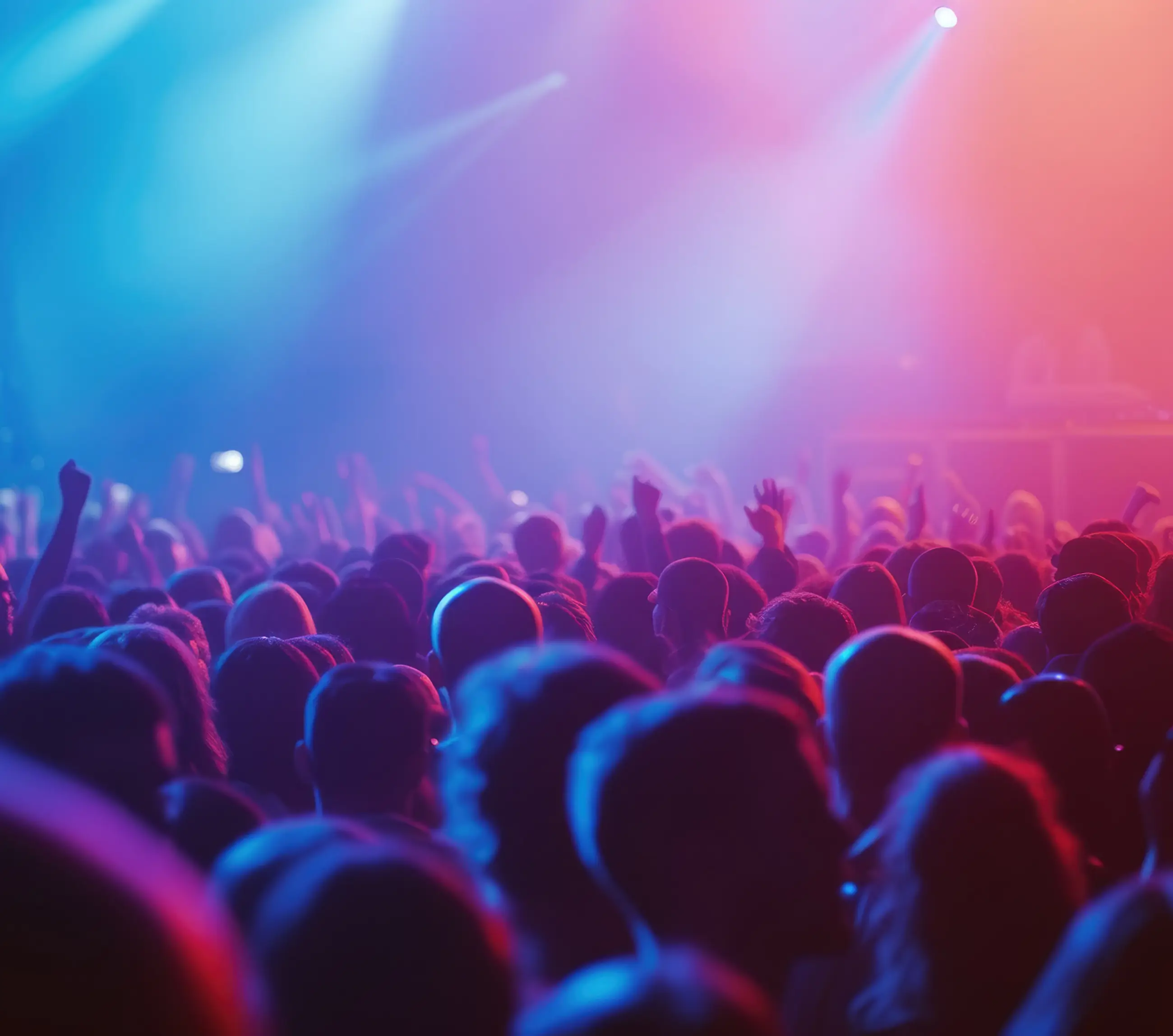Crowd of people at a concert or event with raised hands under blue and pink stage lights.