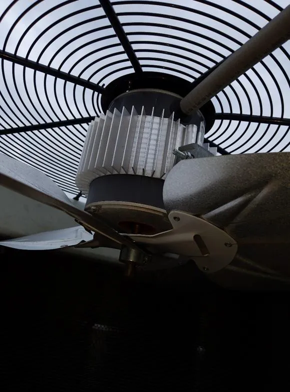 Close-up view of an electric motor with cooling fins and fan blades behind a circular protective grille.
