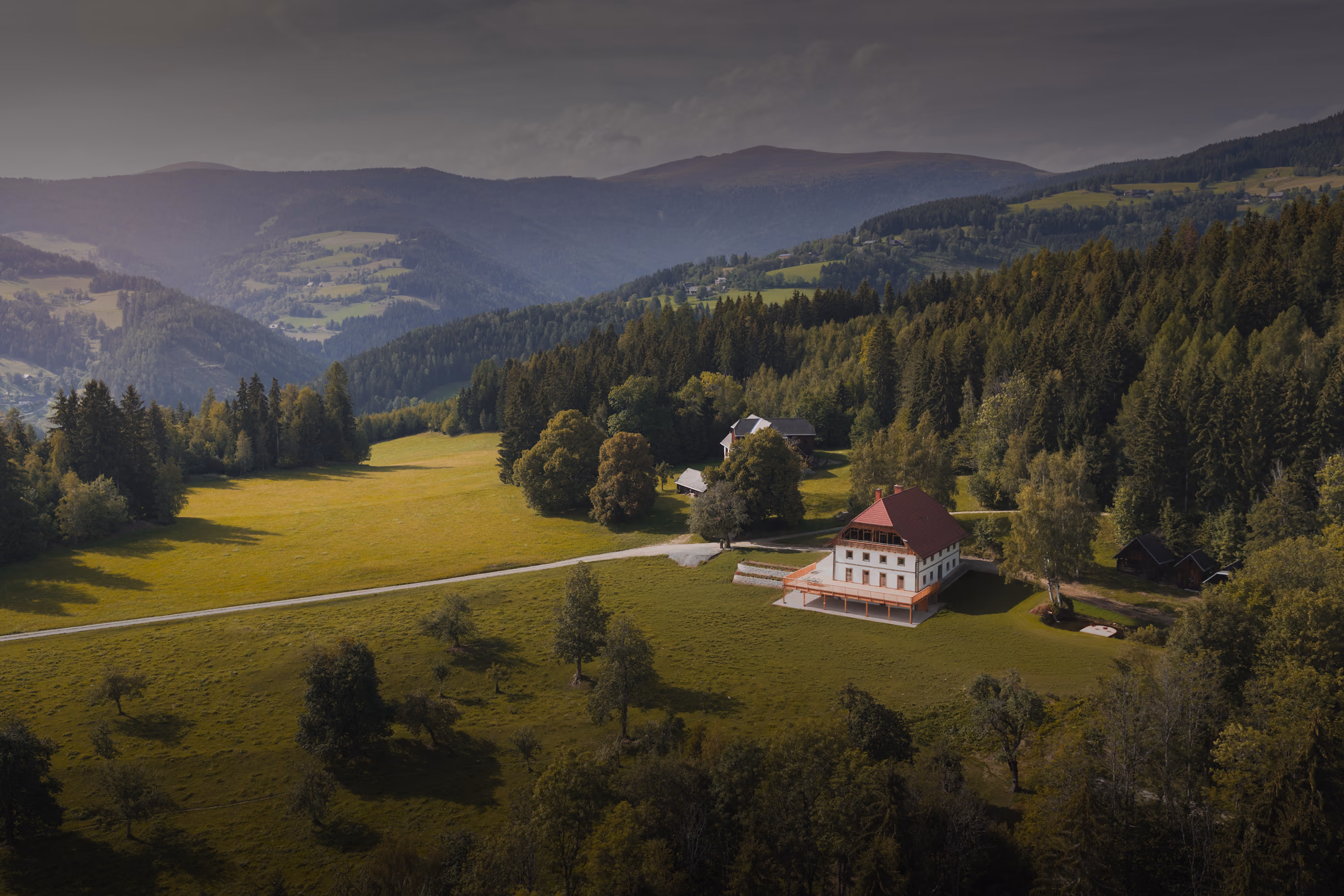 Luftaufnahme zeigt den Gregorhof in einem idyllischen Waldstück in einer Berglandschaft.