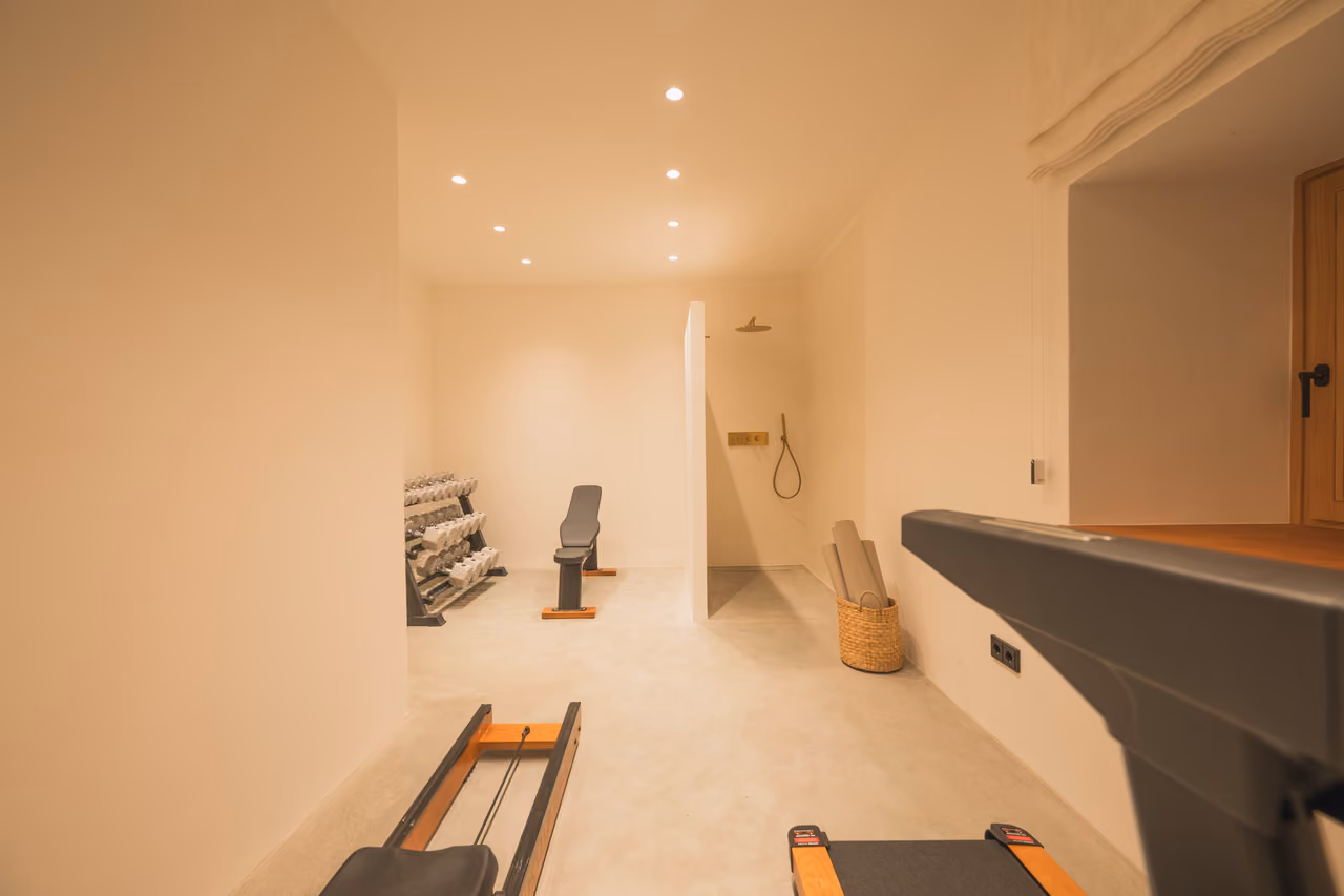 Fitnessraum im Gregorhof mit Hantelbank, Hanteln, Rudermaschine und Dusche.